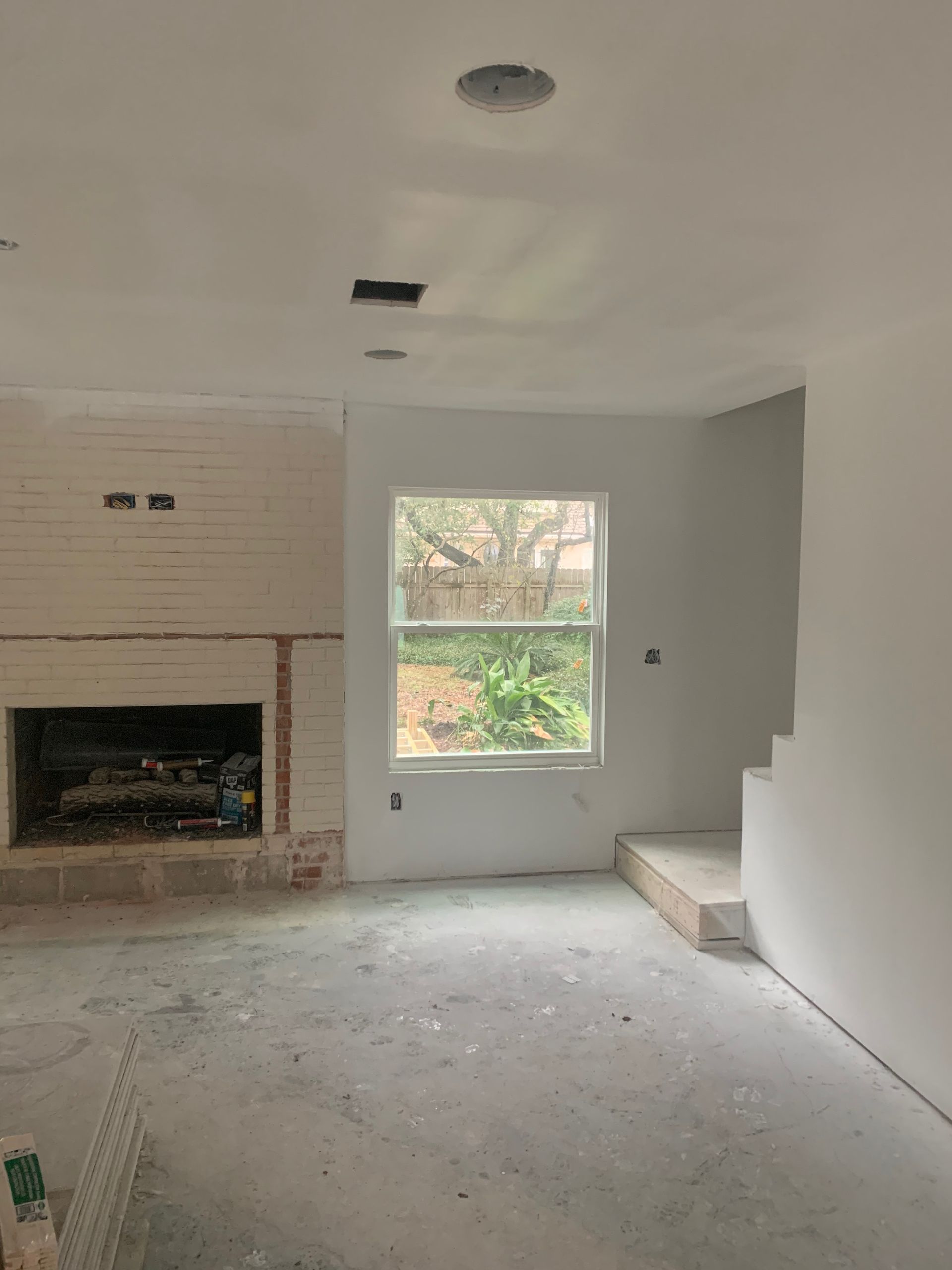 An empty living room with a fireplace and a window.