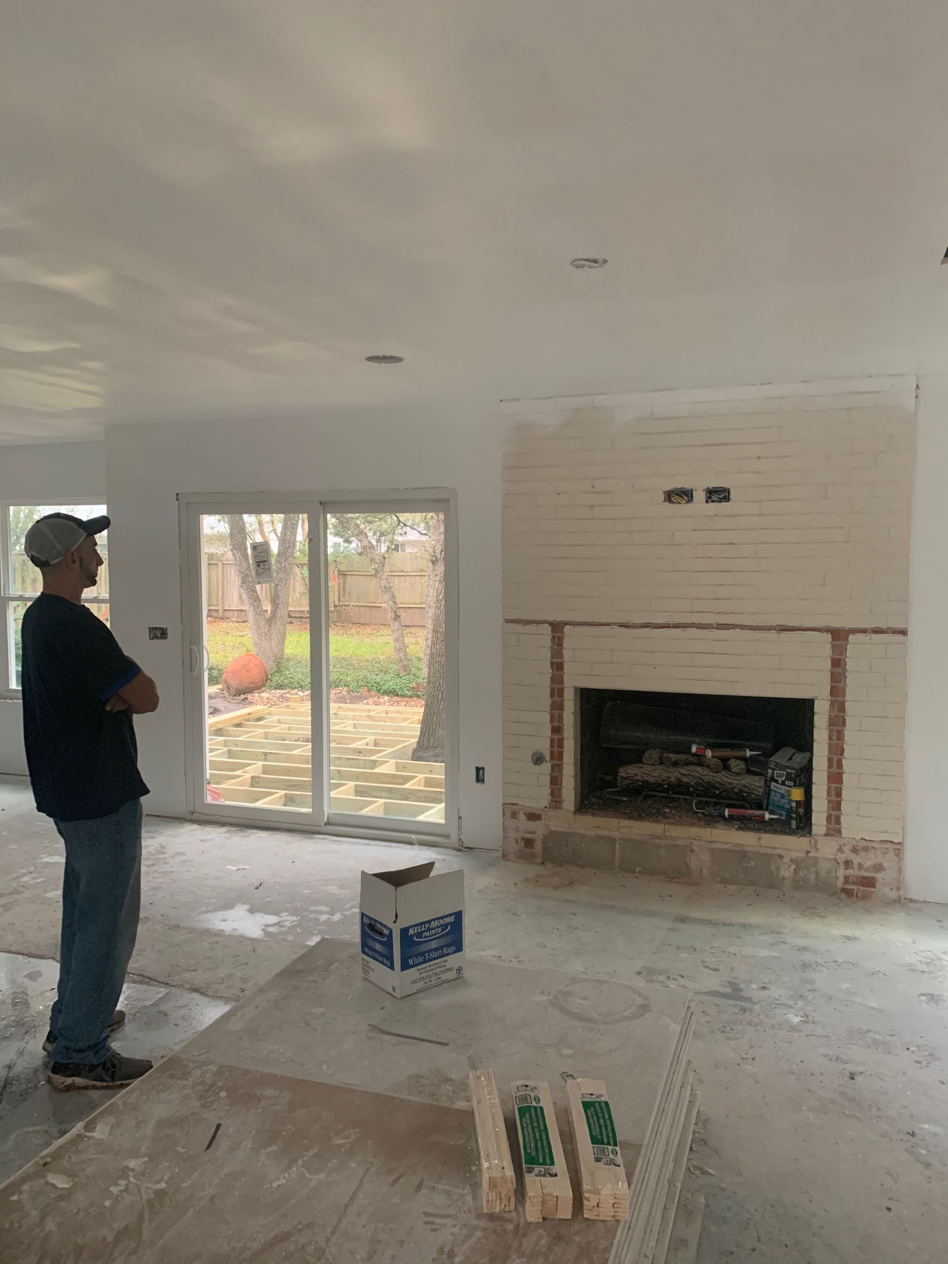 A man is standing in a living room in front of a fireplace.