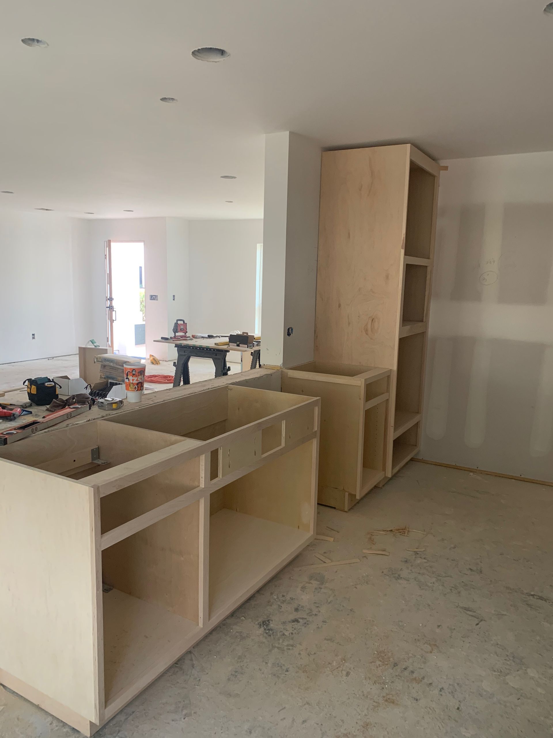A kitchen under construction with wooden cabinets and shelves.