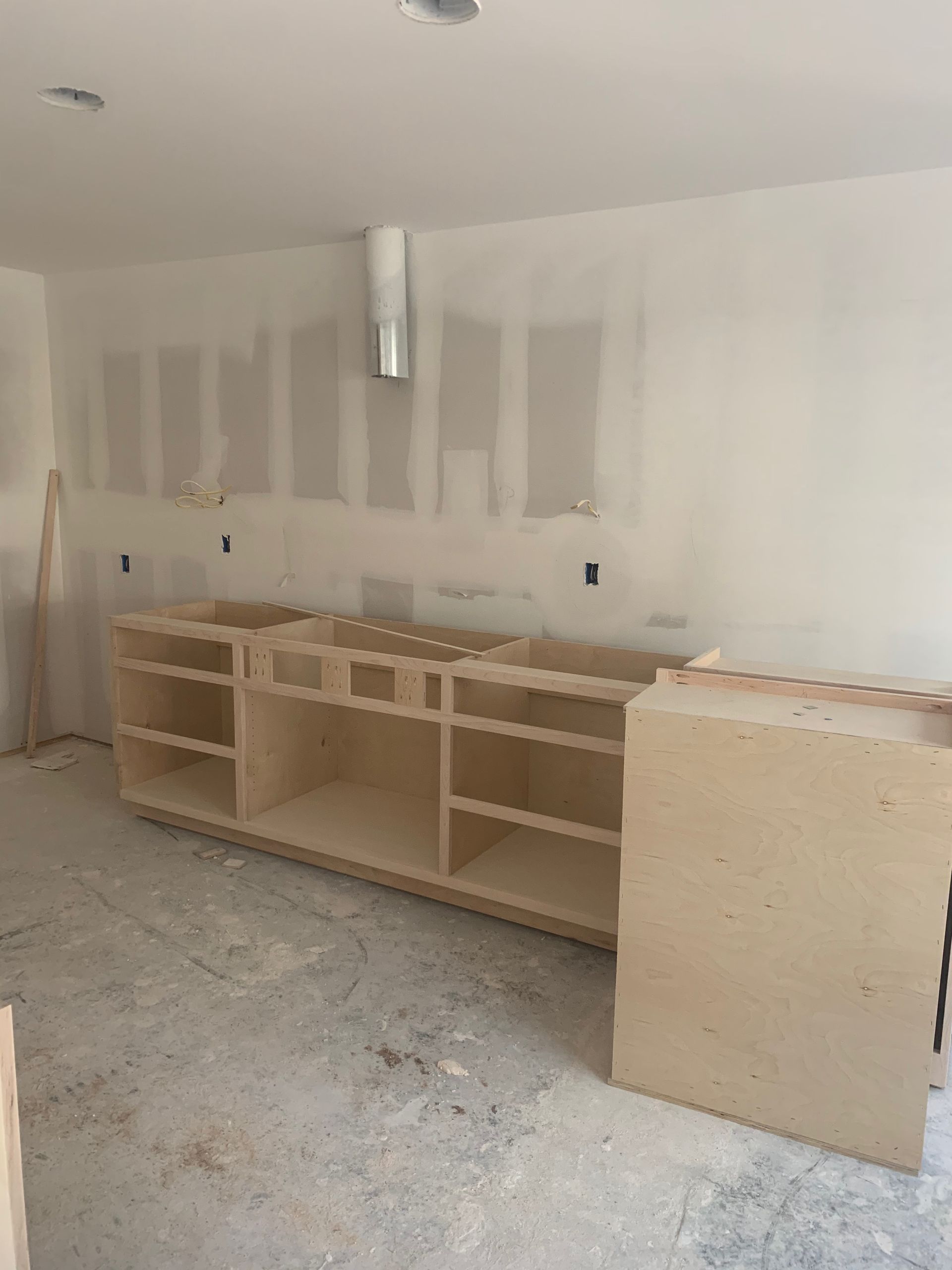 A kitchen under construction with wooden cabinets and a ceiling fan.