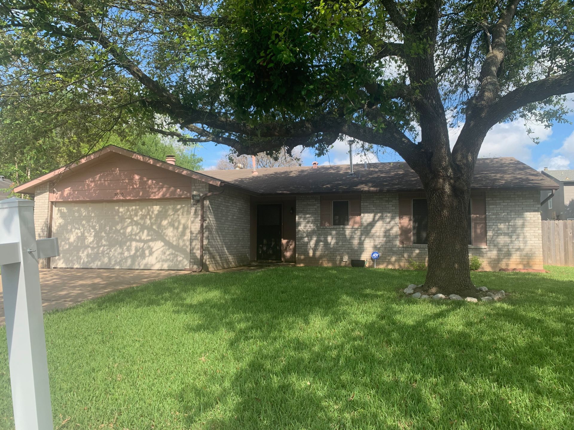A house with a tree in front of it and a white fence.