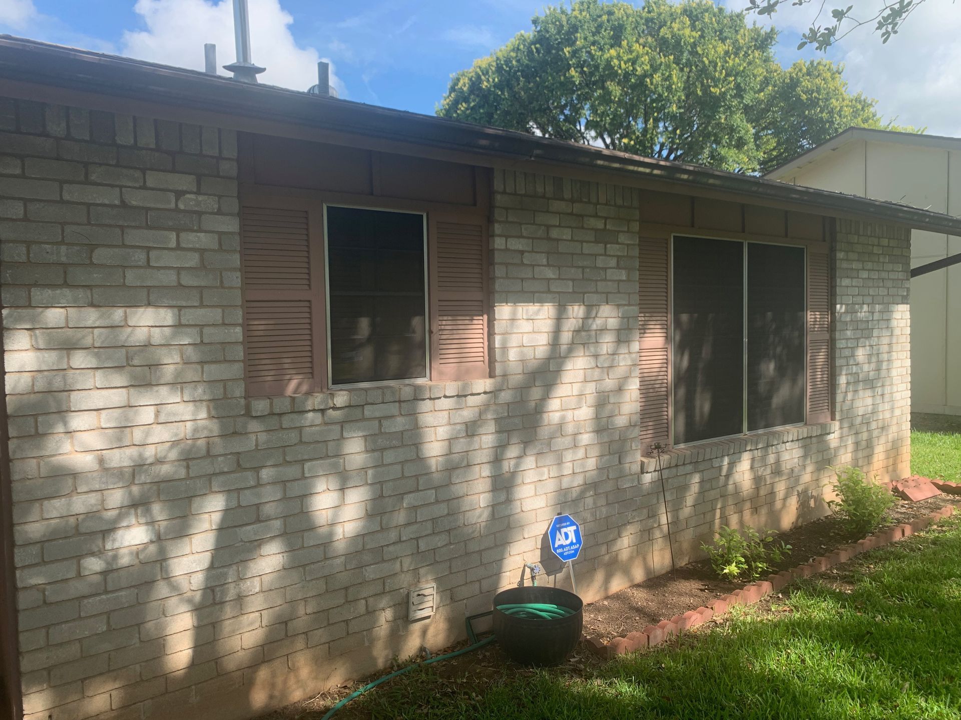 The back of a white brick house with shutters on the windows.