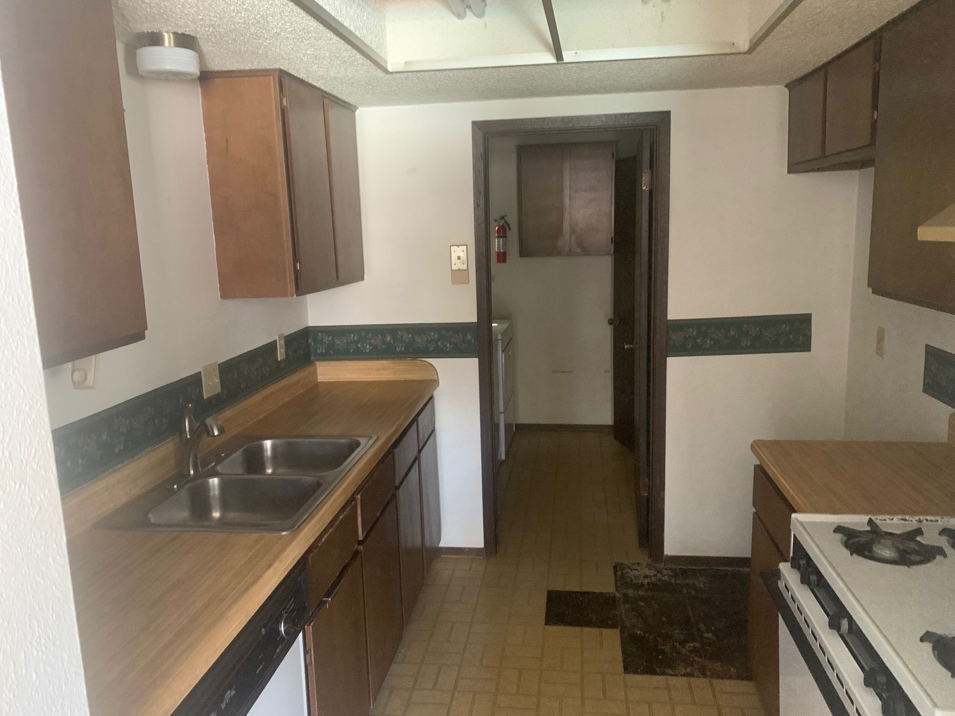 An empty kitchen with a sink stove and dishwasher.