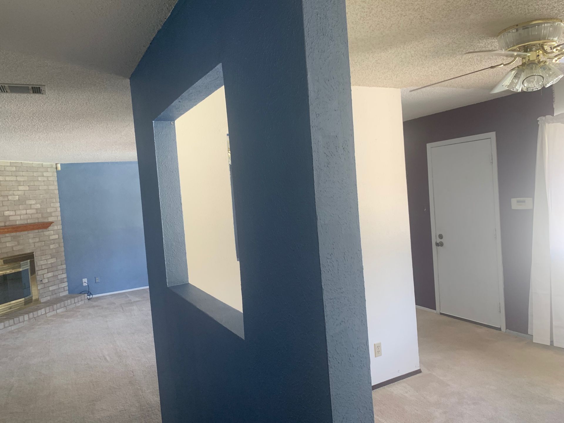 A living room with blue walls and a ceiling fan.