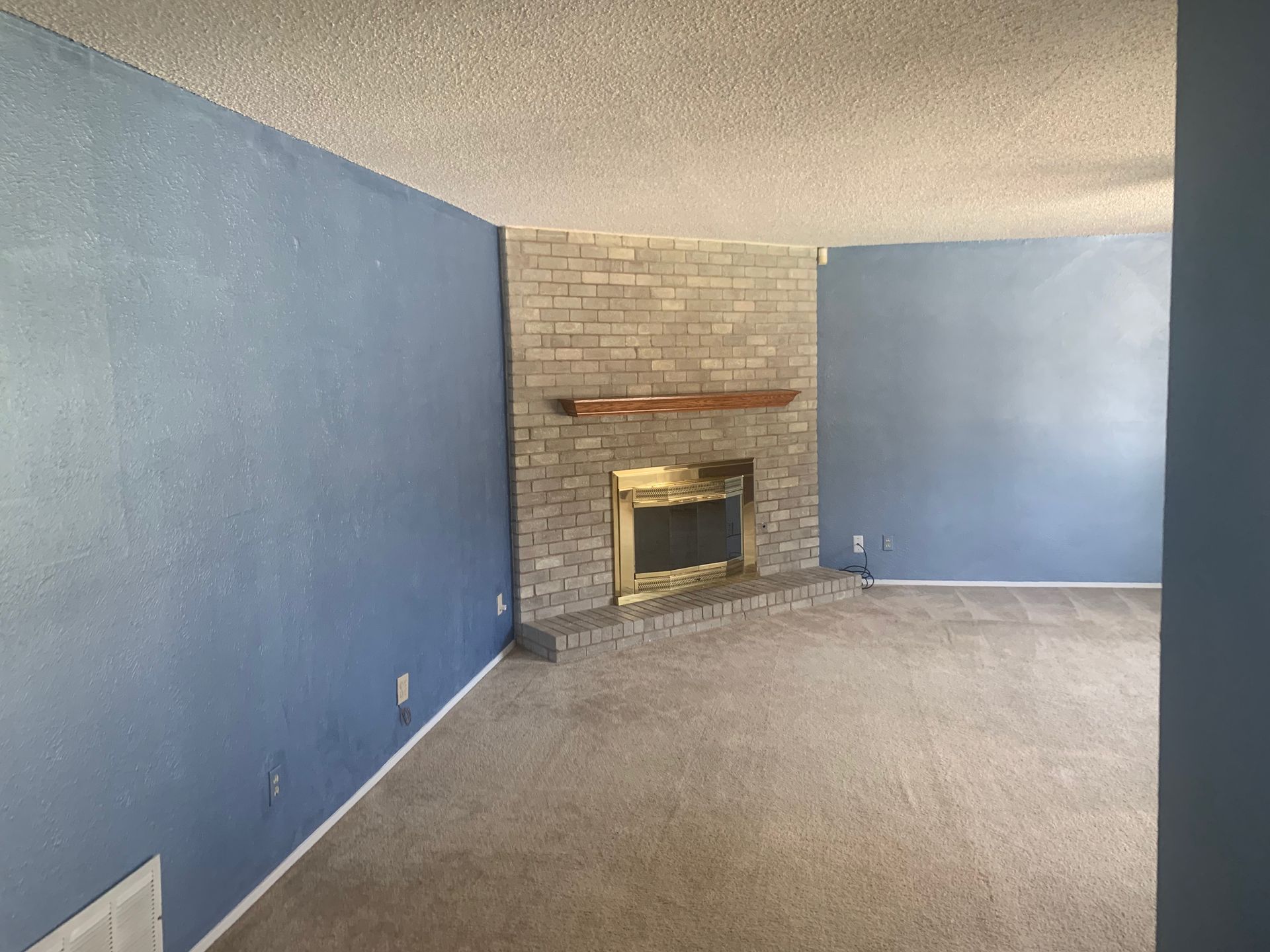 An empty living room with a fireplace and blue walls.