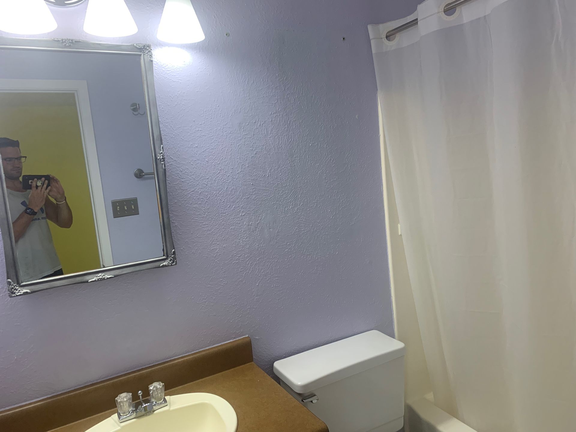 A bathroom with a toilet, sink, mirror, and shower curtain.