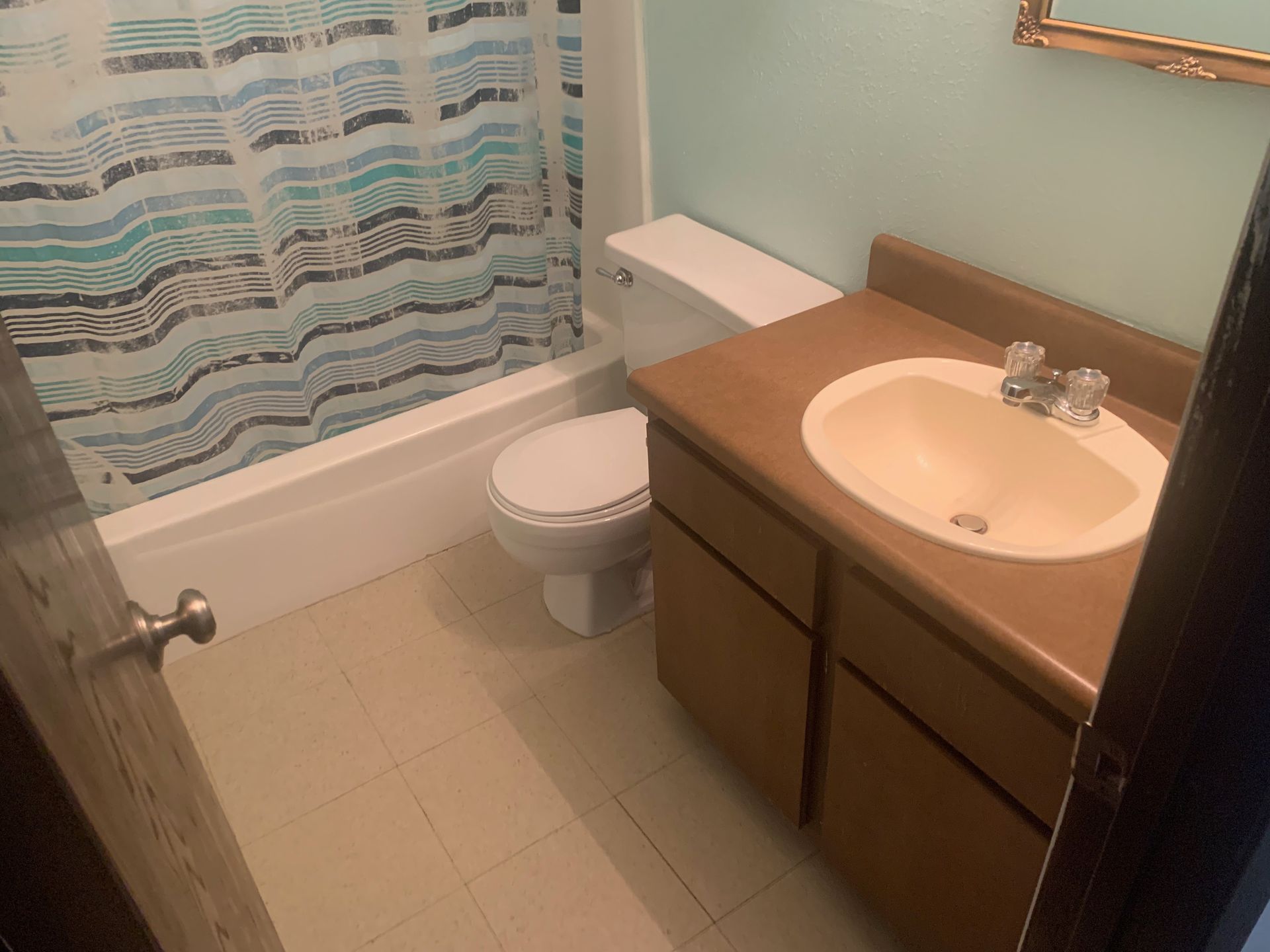 A bathroom with a toilet, sink, and shower curtain.