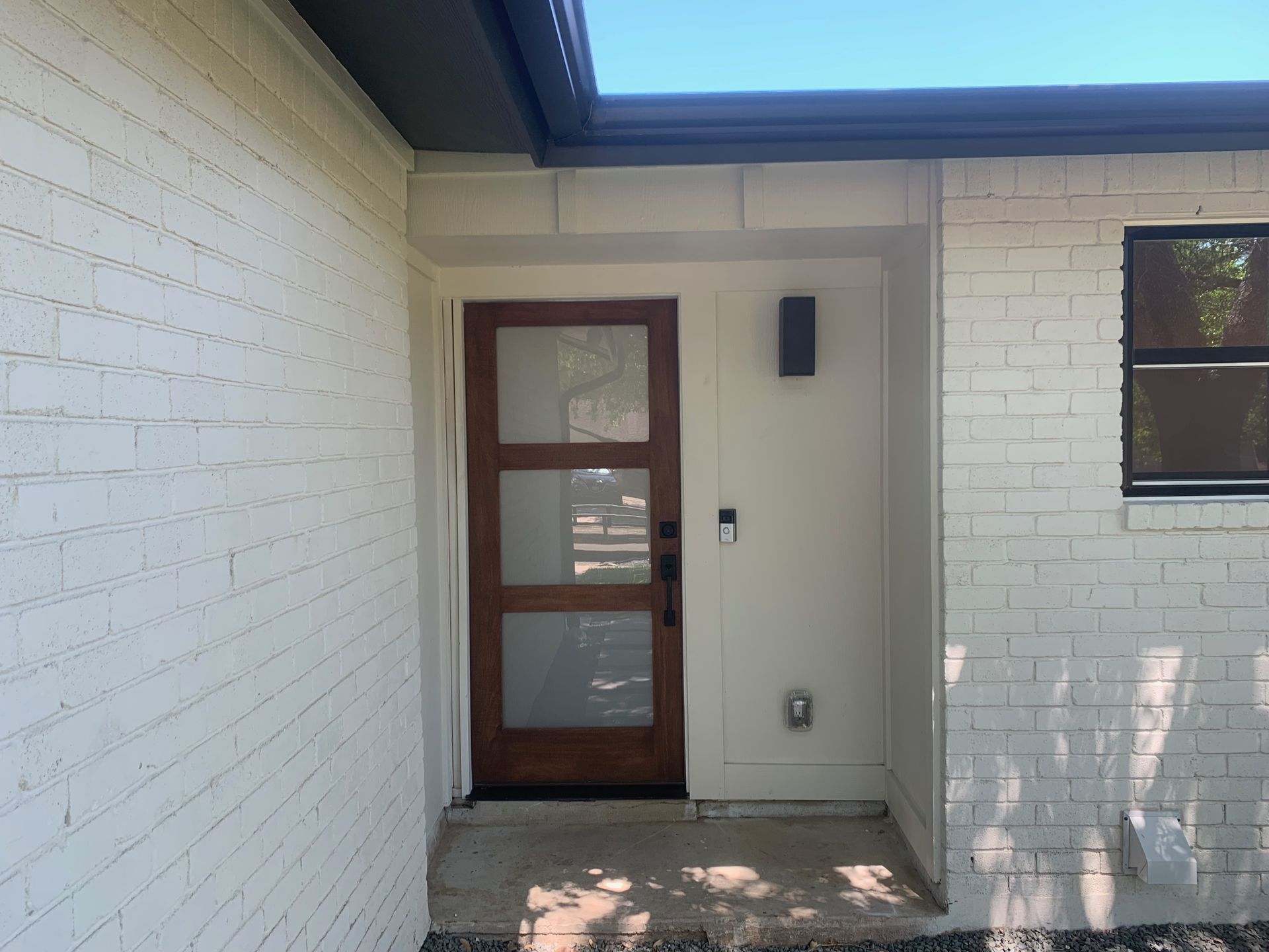 A white brick house with a brown door.