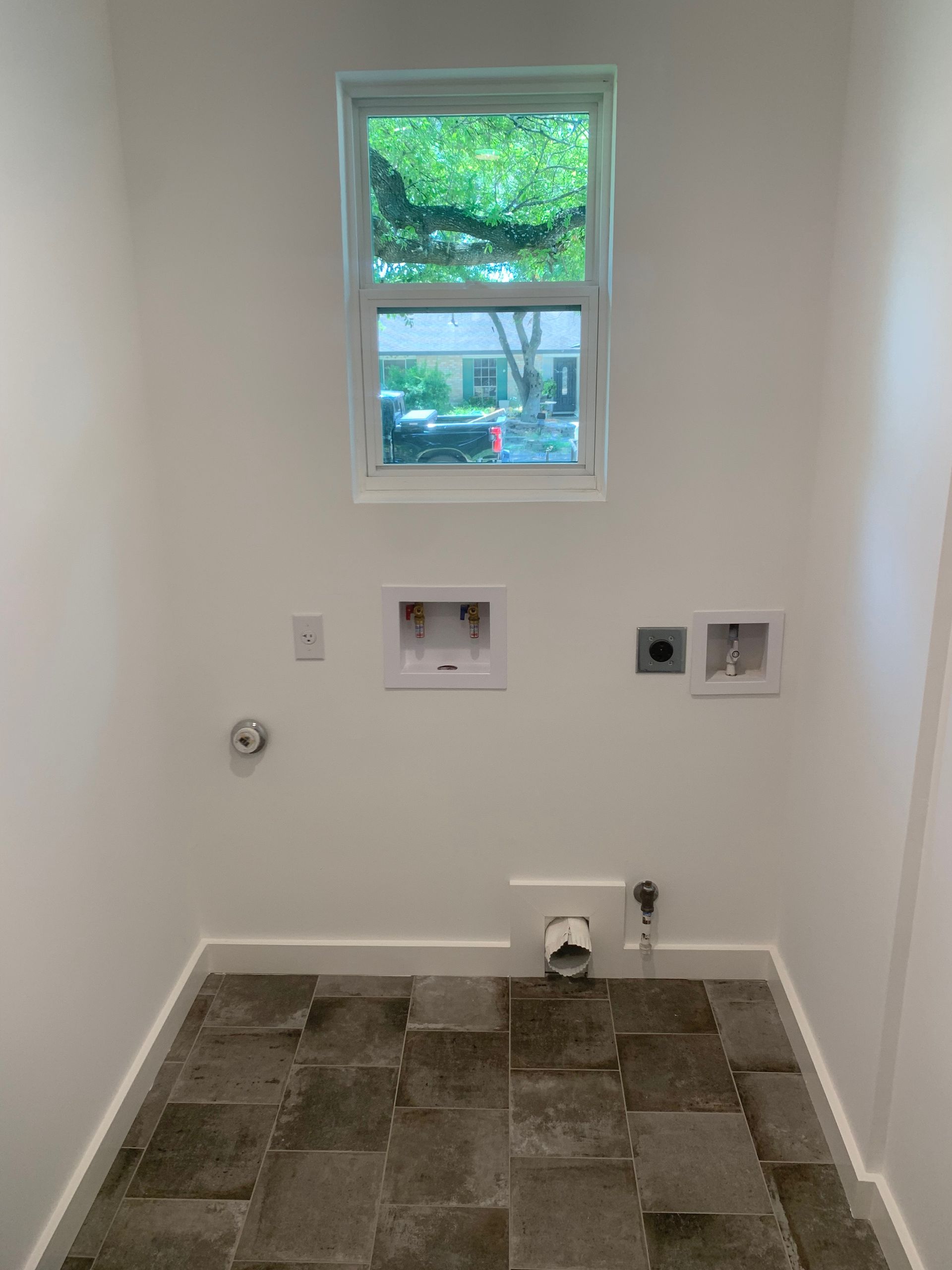 A laundry room with a window and tile floor.