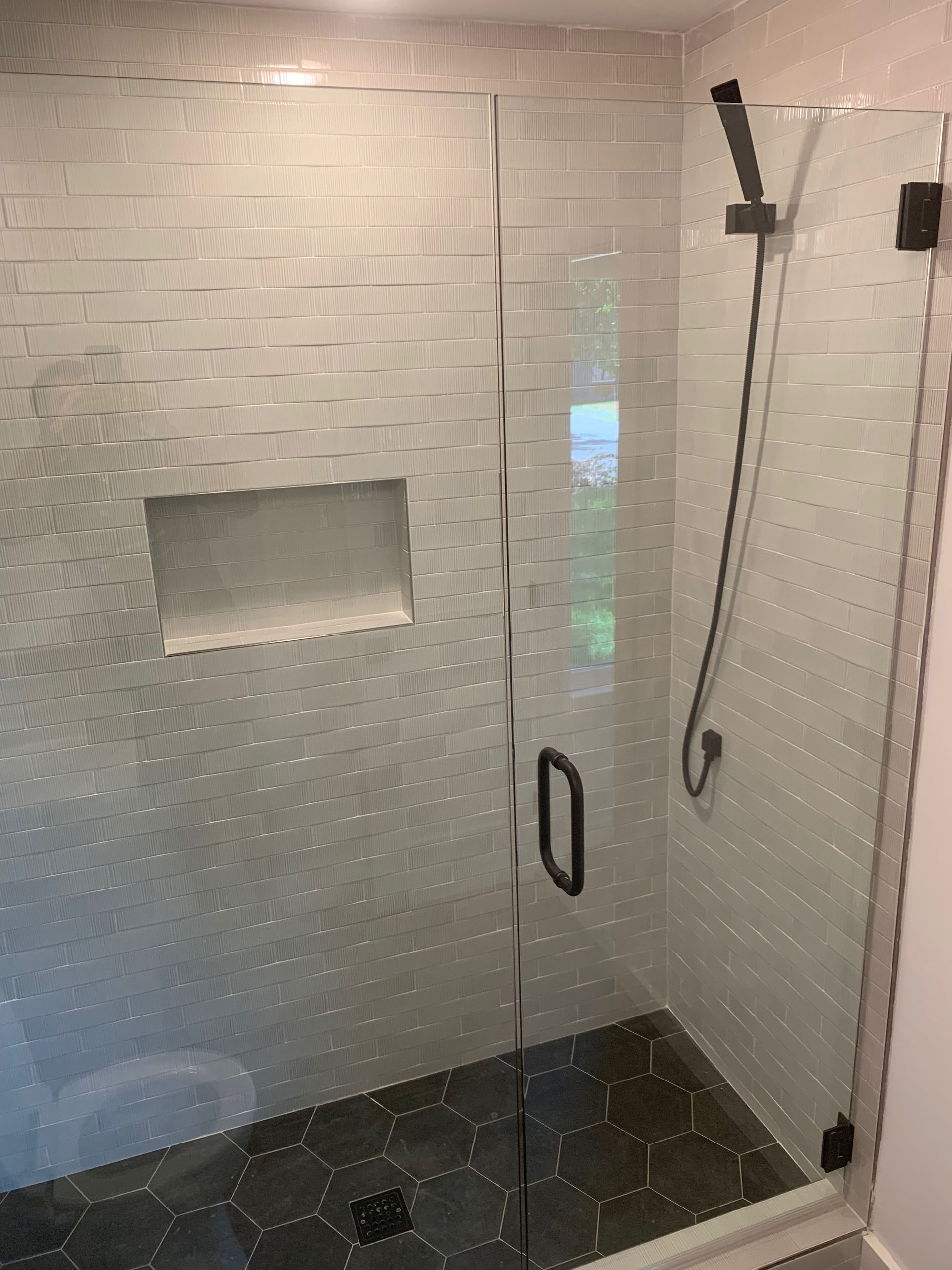 A shower stall with a glass door and a shower head.