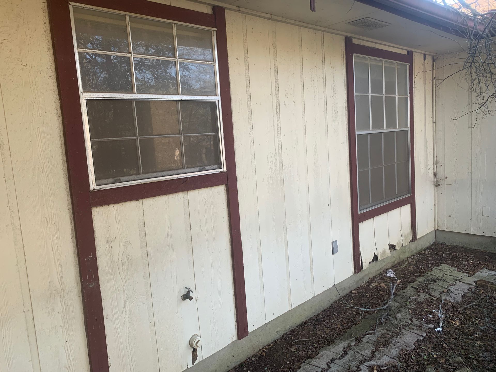 There are two windows on the side of a house.