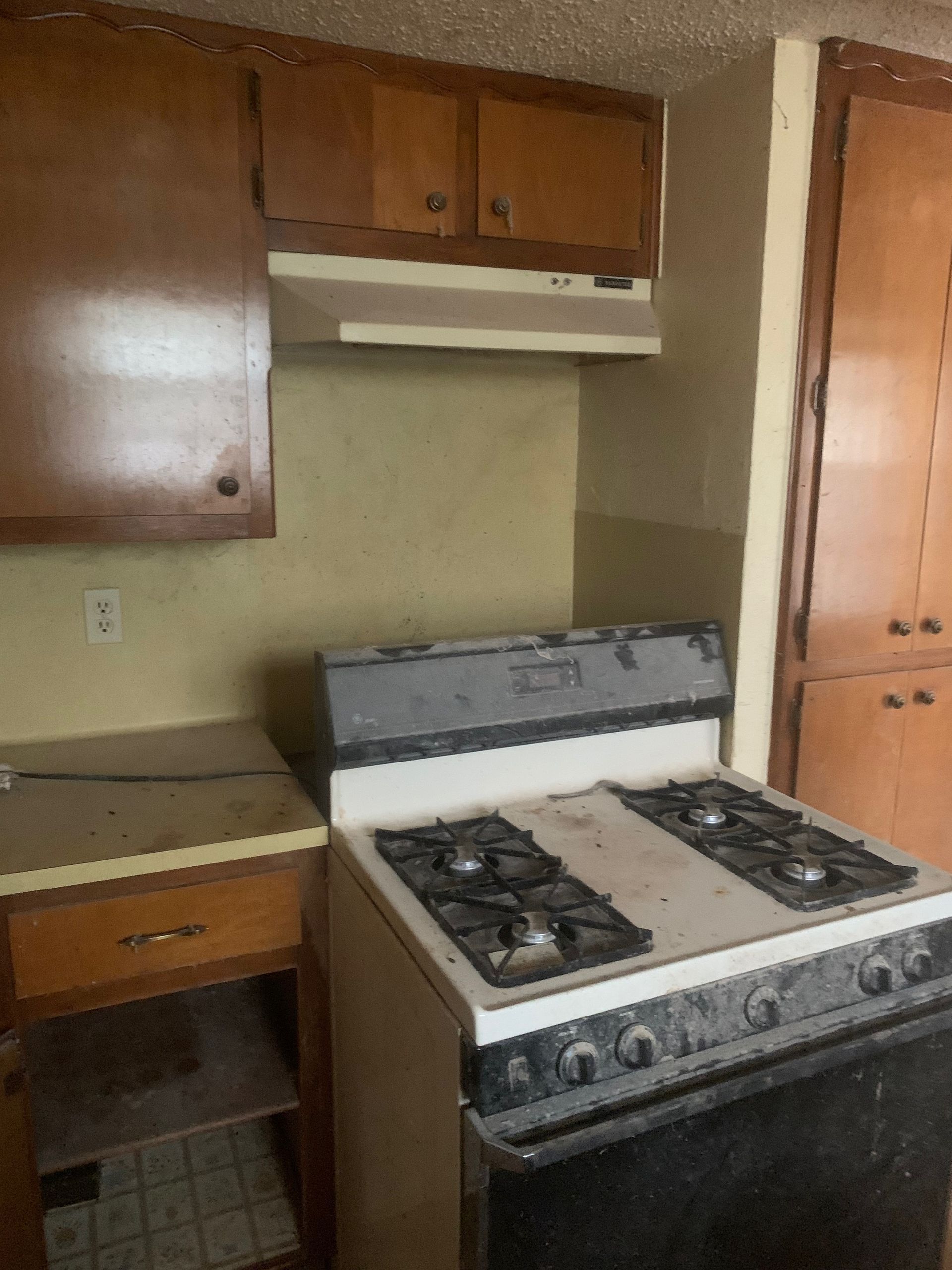 A kitchen with a stove top oven and cabinets.