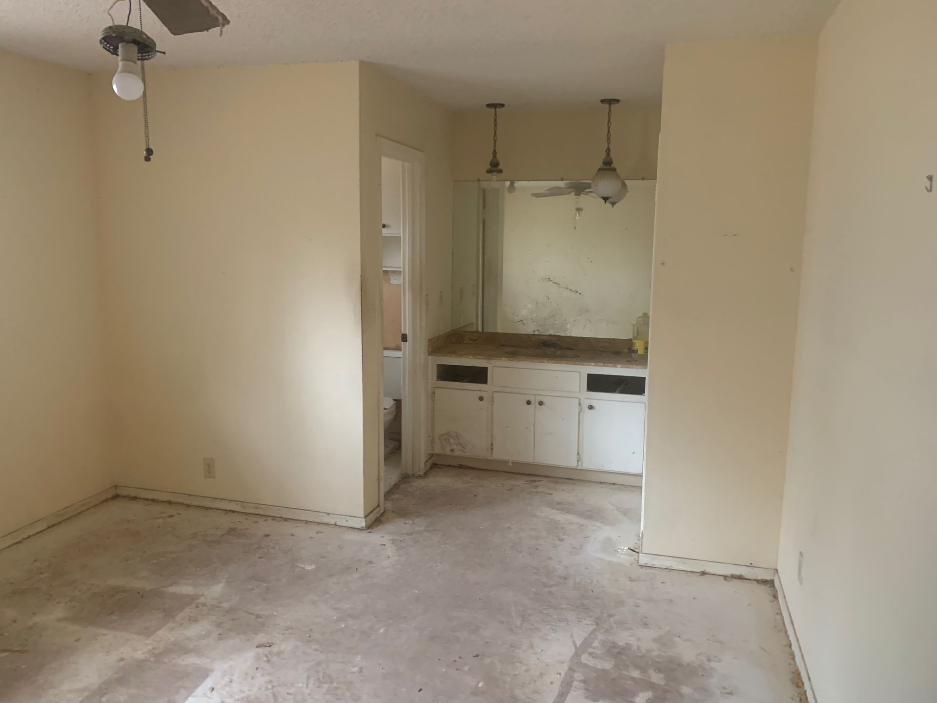 An empty room with a ceiling fan and a sink.