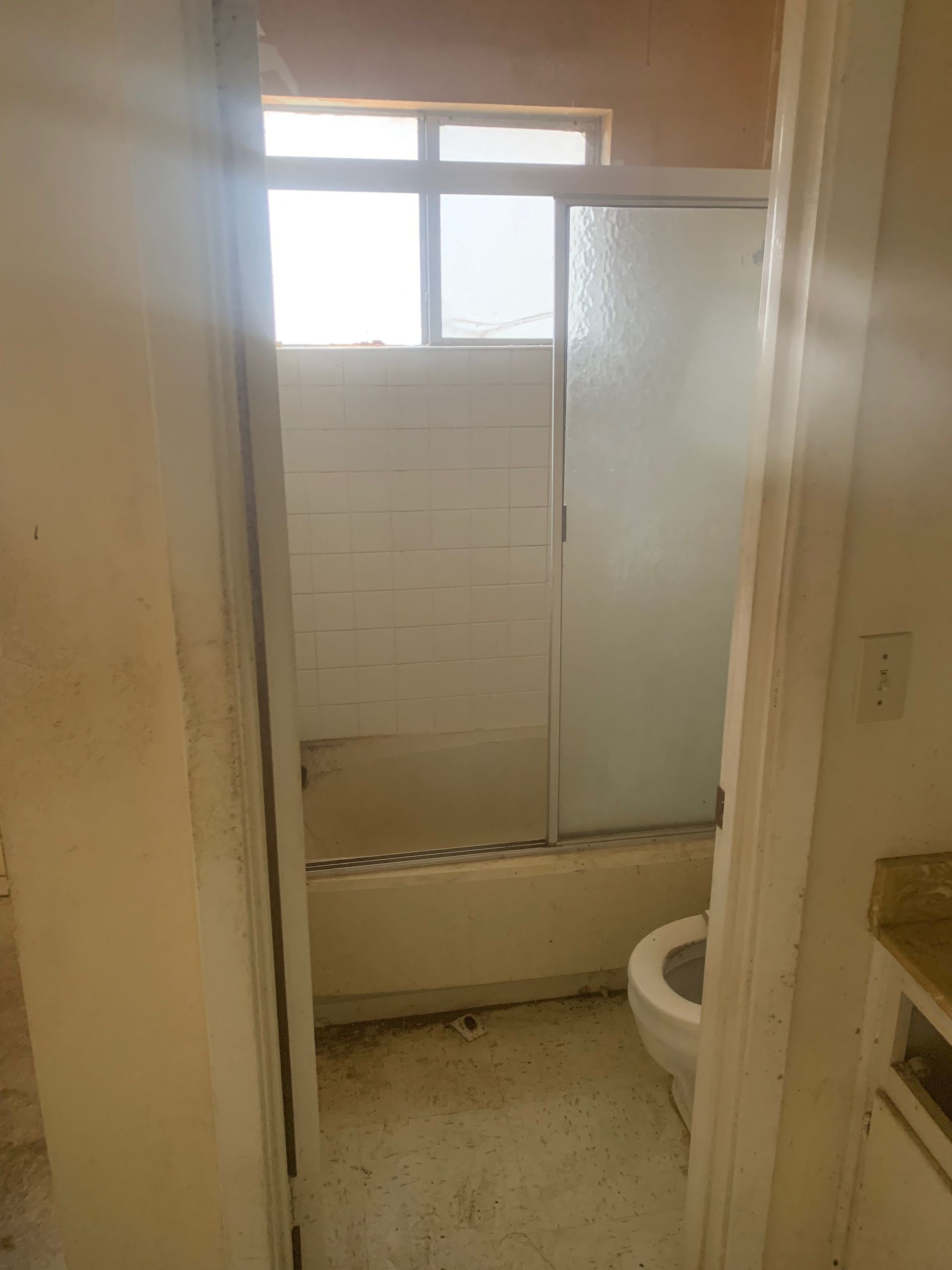 A bathroom with a toilet, tub, shower, and window.