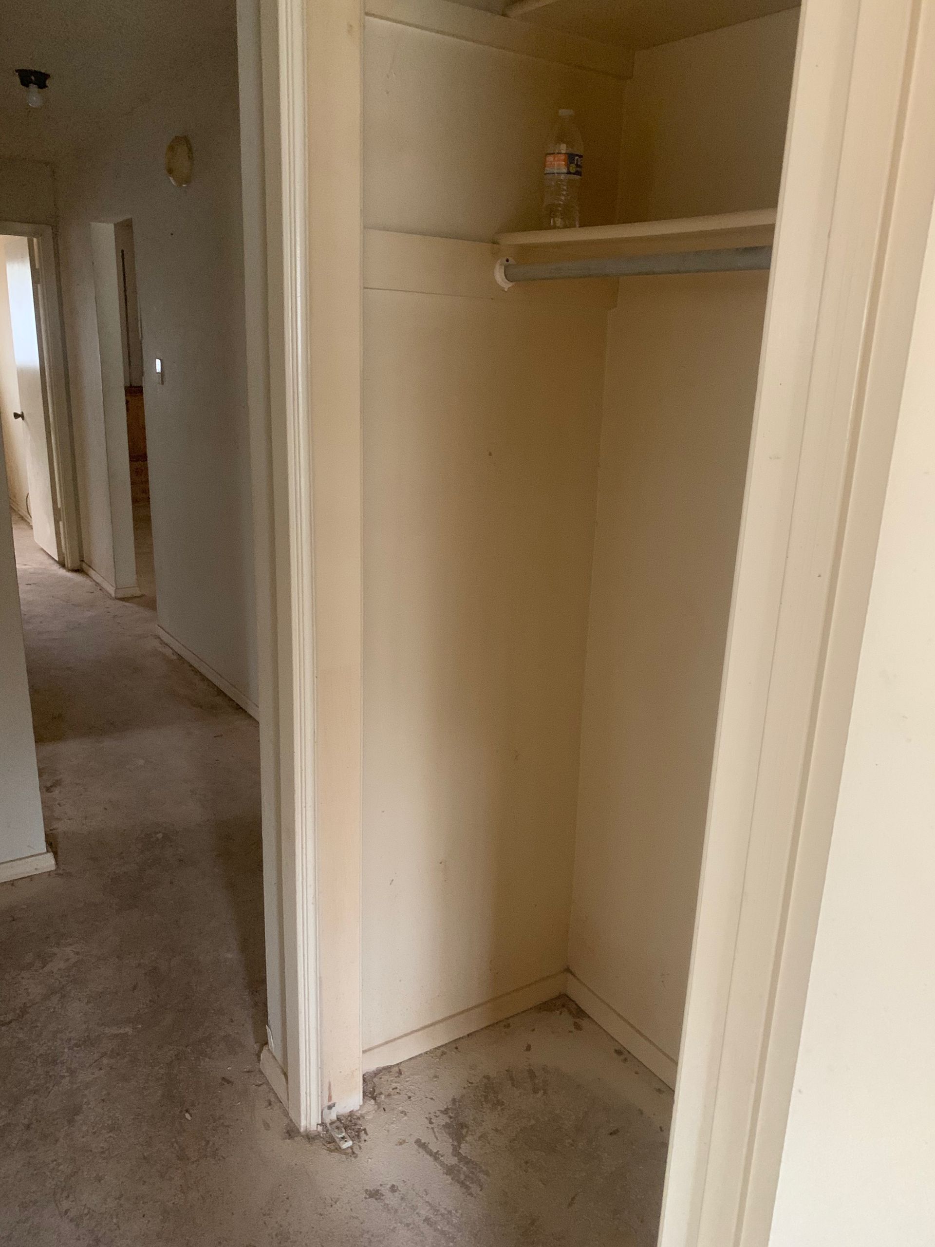 There is a bottle of water on the shelf in the closet.