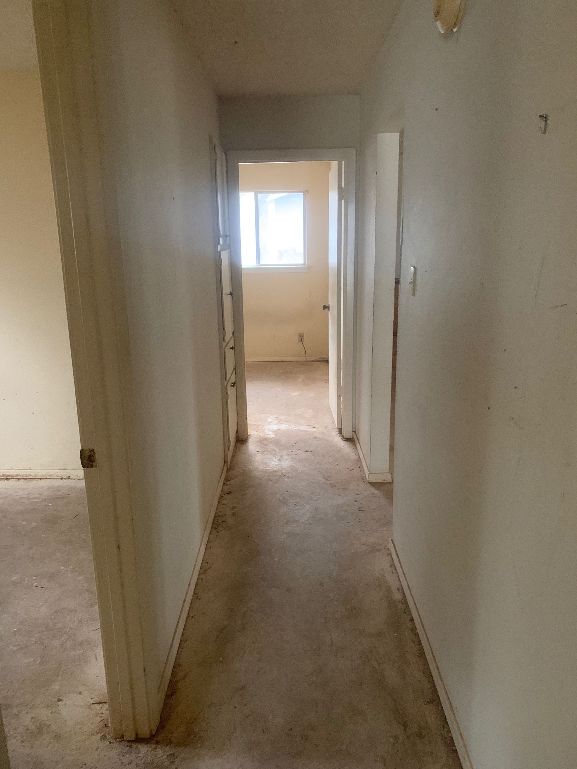 A long hallway leading to a room with a window.