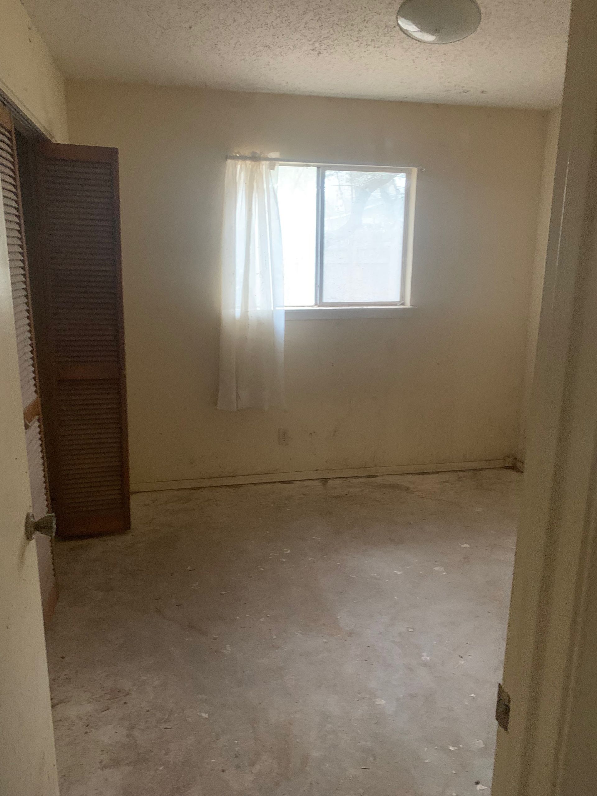 An empty room with a window and a door.