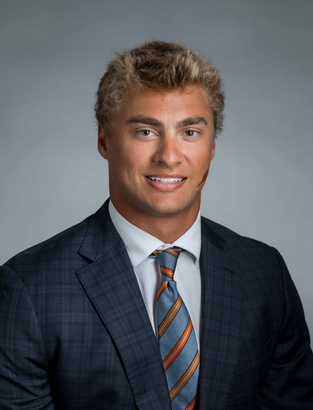 Professional headshot of Campbell D. Klein in a dark suit with a striped tie against a gray background