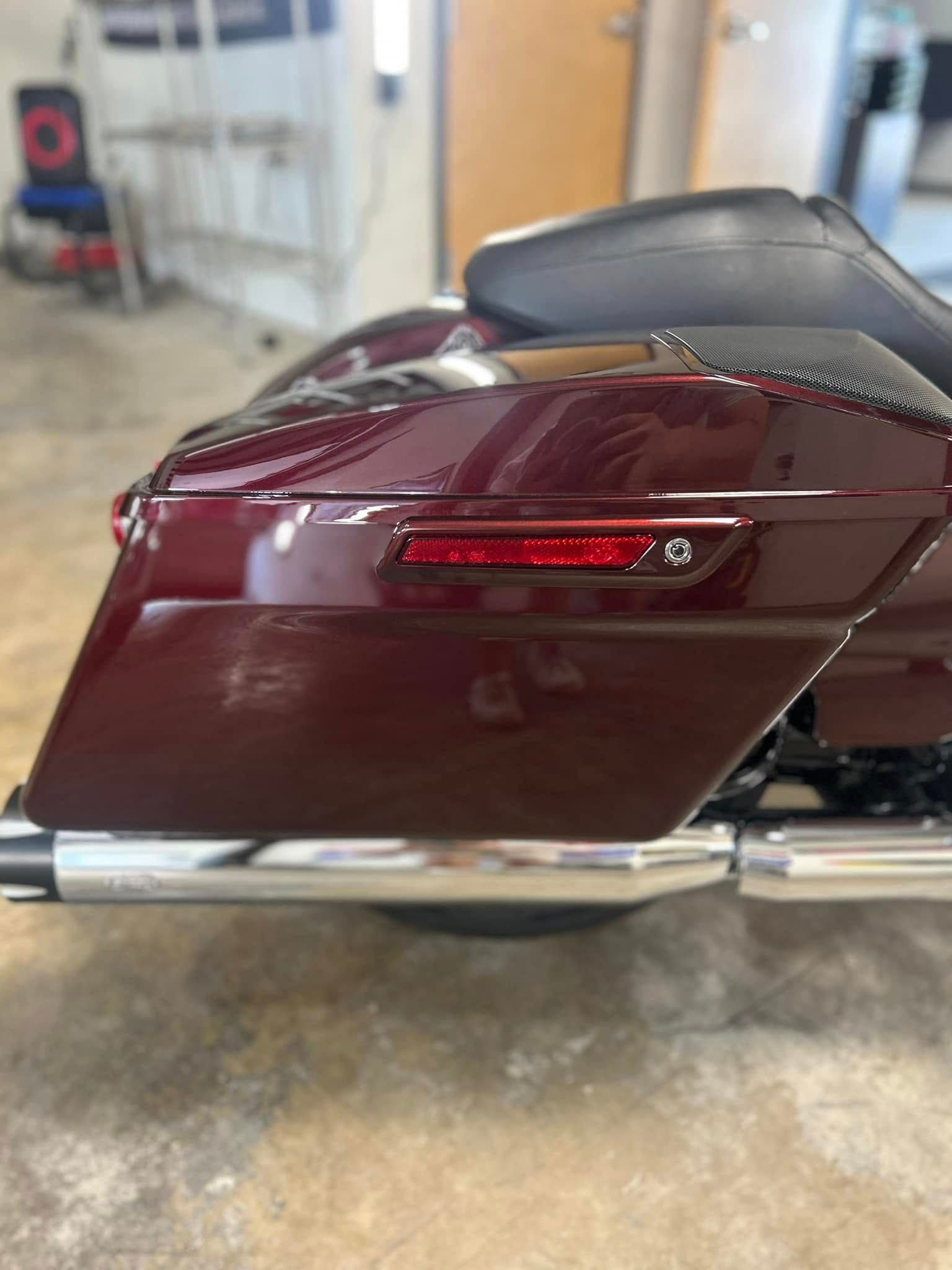 Maroon touring motorcycle with chrome exhaust and rear red taillight in a garage