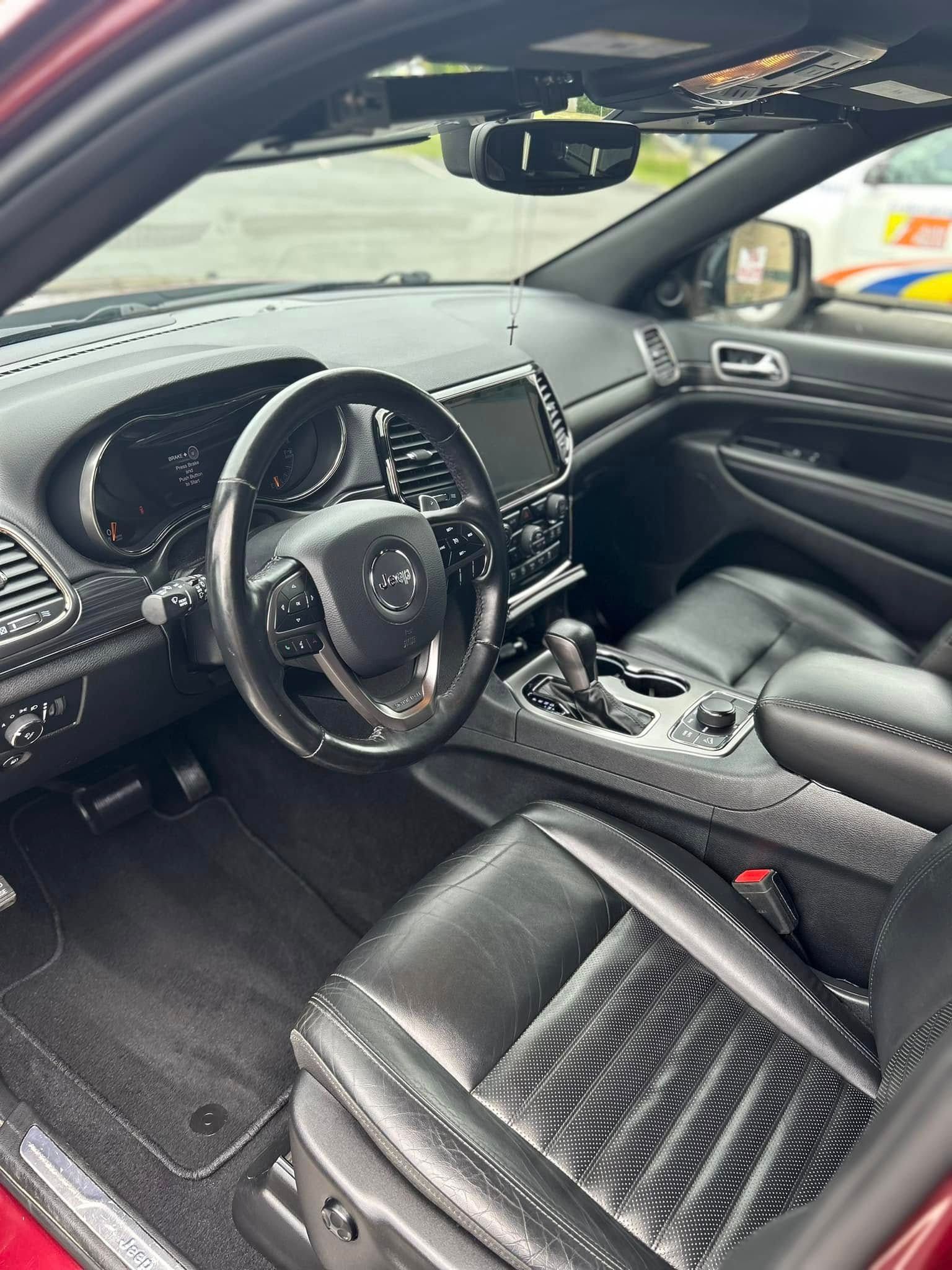 Car interior with black leather seats, dashboard, and center console, viewed from the driver’s side.