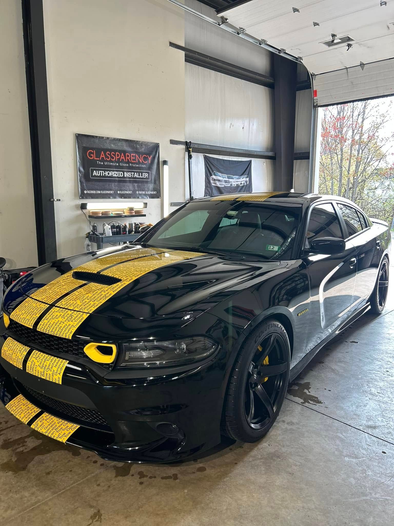 Black sports car with yellow racing stripes parked inside a garage