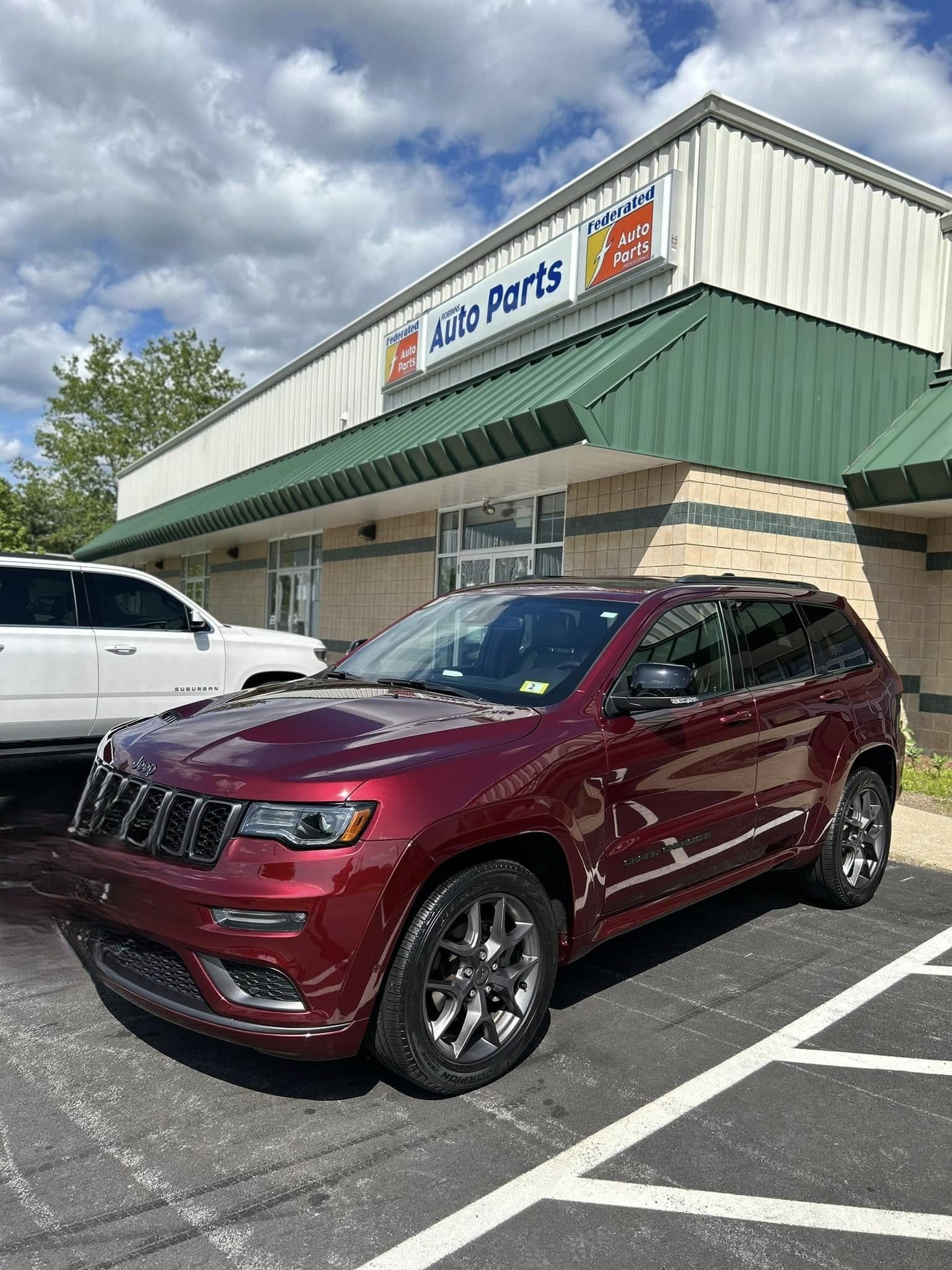 Maroon SUV parked outside a Napa Auto Parts store under a cloudy sky