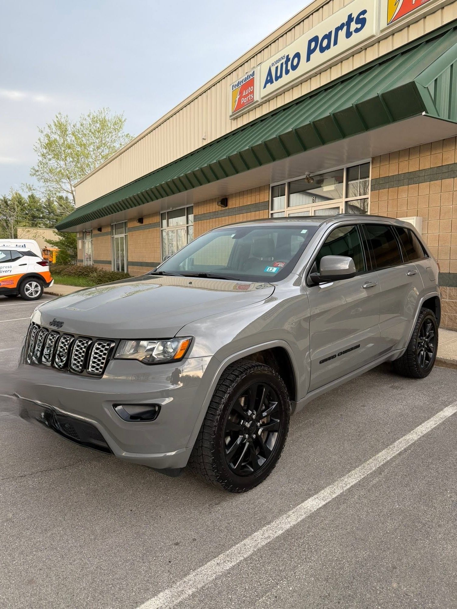 Gray Jeep Grand Cherokee parked outside an Auto Parts store