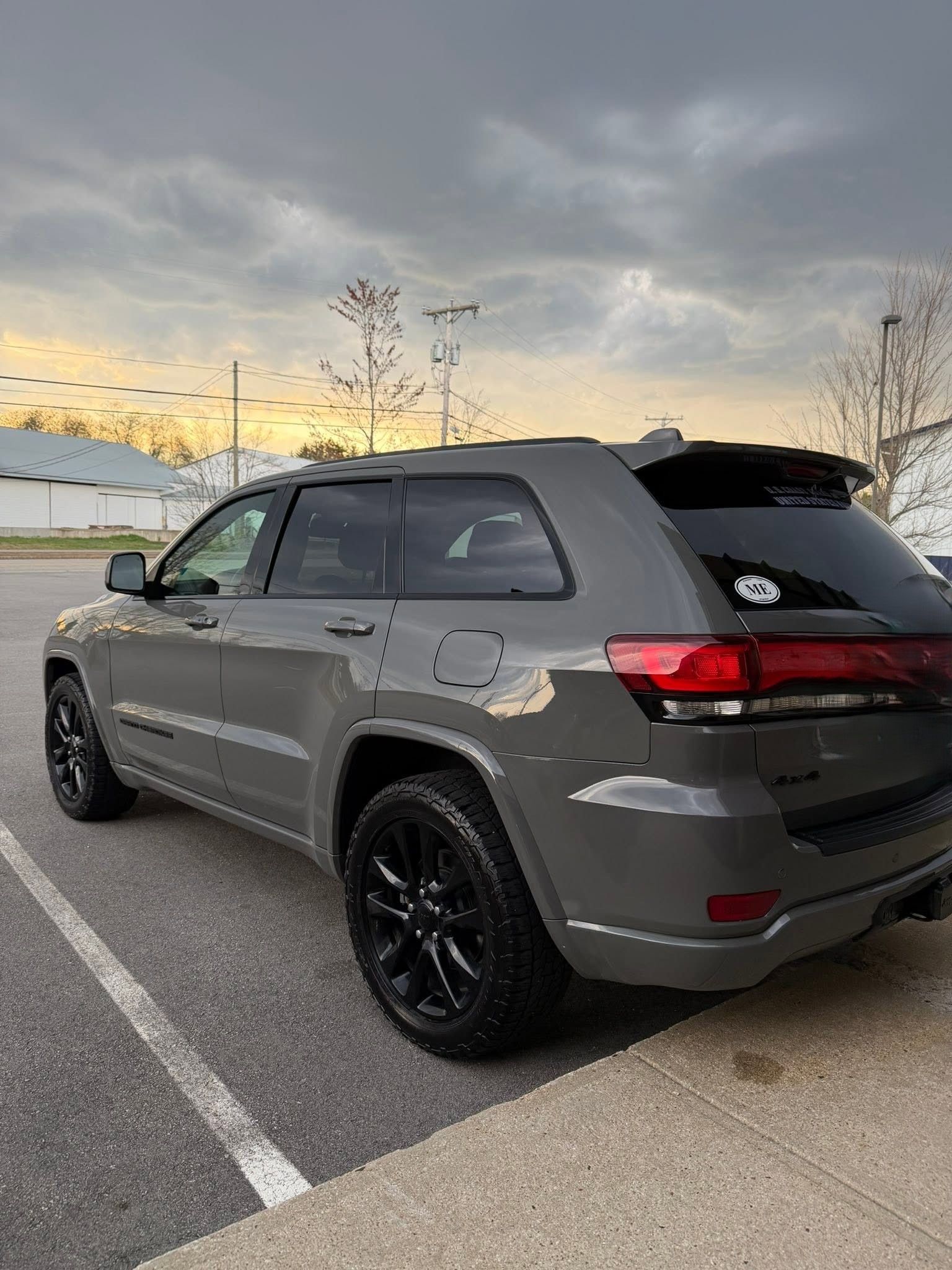 Gray SUV parked in a lot at sunset, viewed from the rear side.