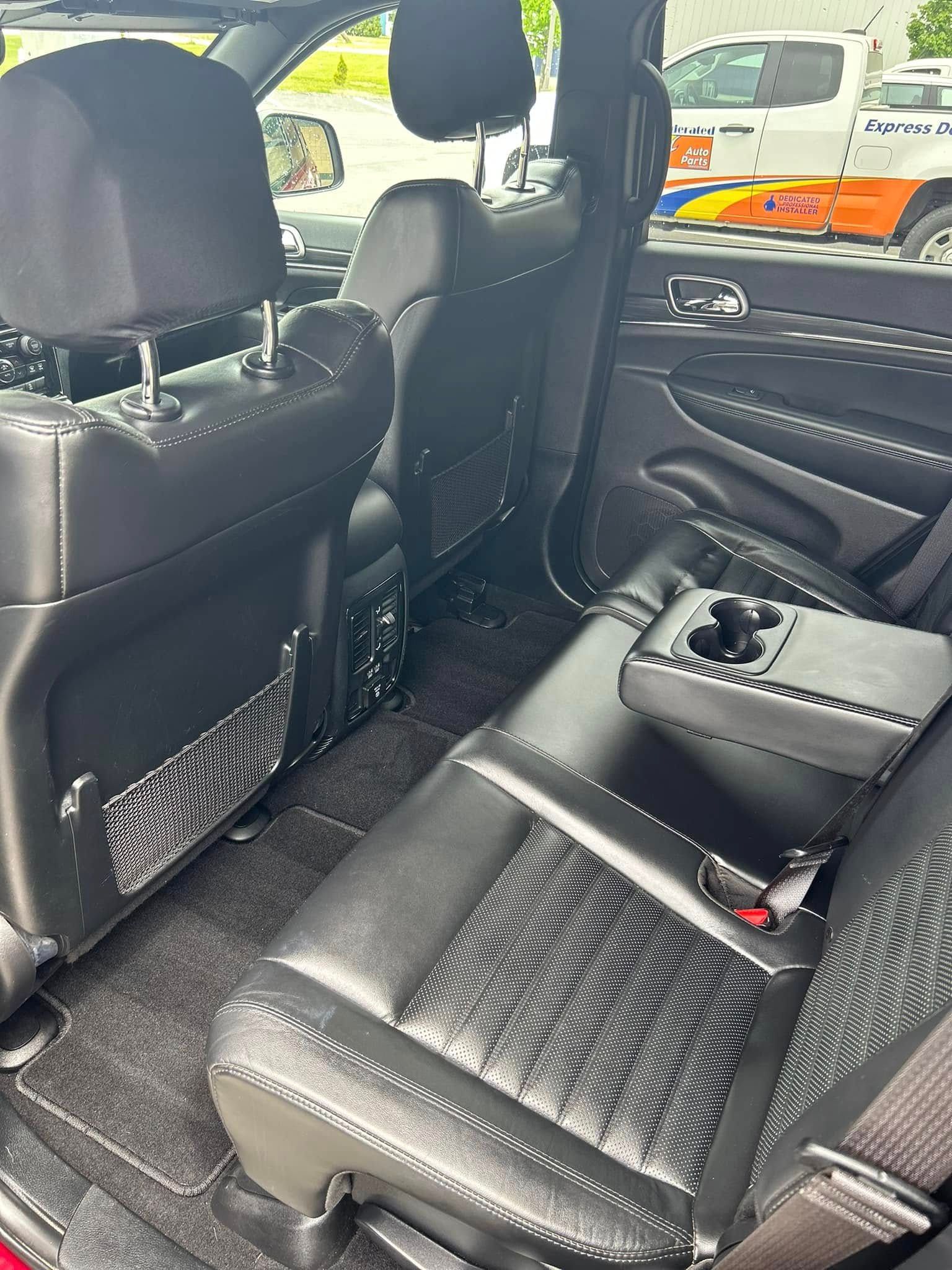 Car interior with black leather seats, a center console, and a patterned seat cover in the back.