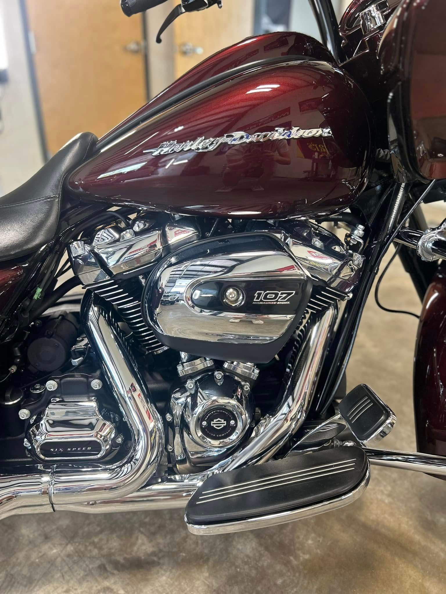 Maroon motorcycle fuel tank and chrome engine with black footboard, side view indoors