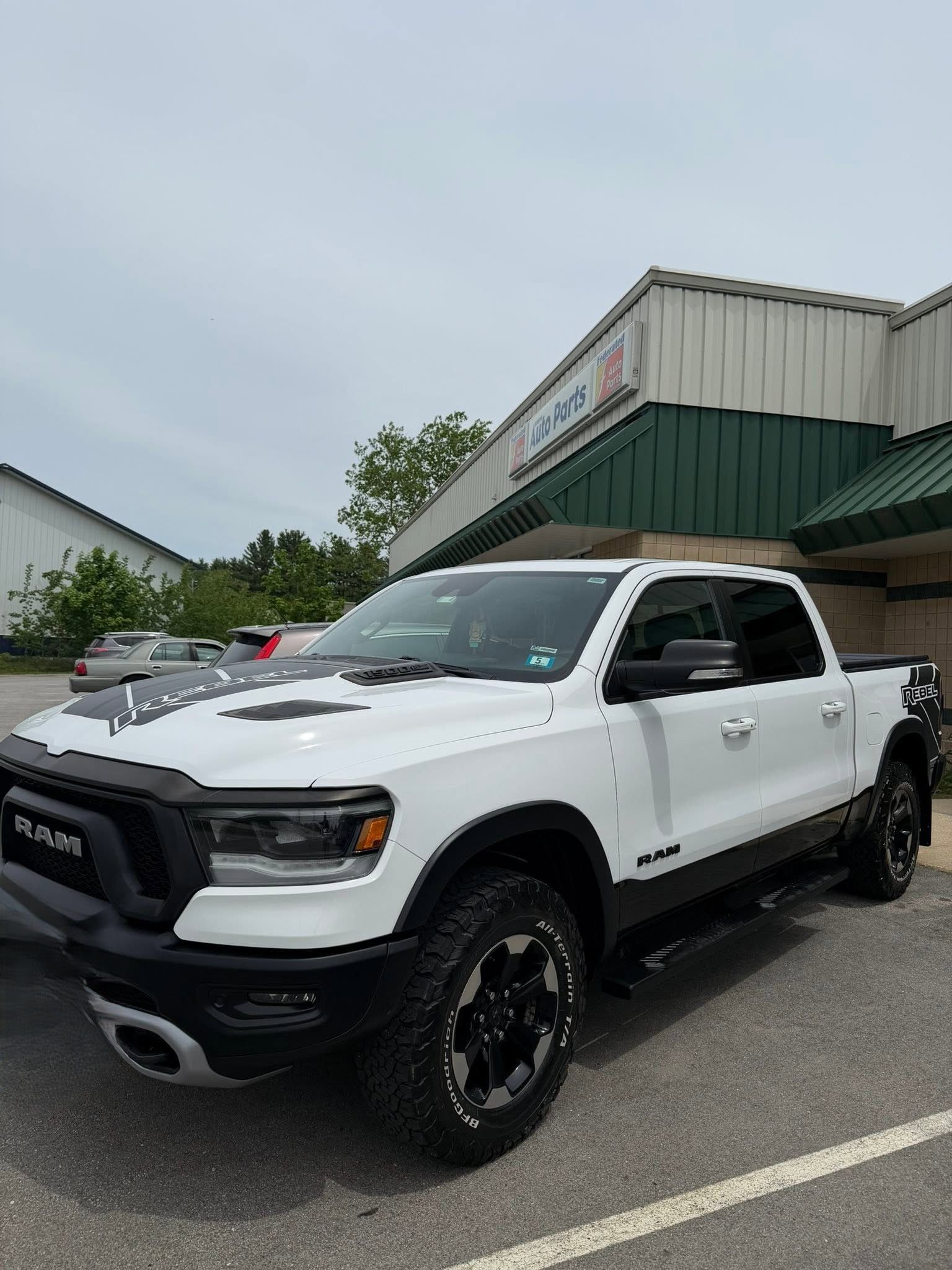 White pickup truck parked outside a building with a green awning on an overcast day