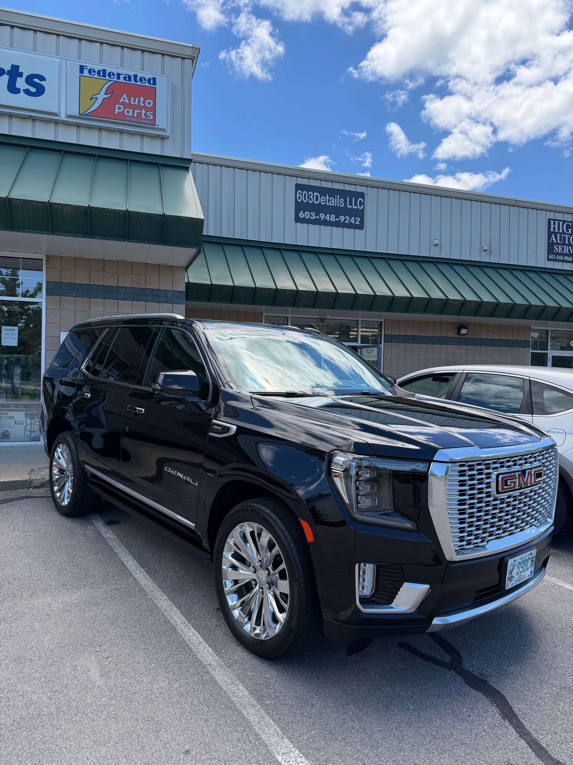Black GMC SUV parked outside a storefront on a sunny day