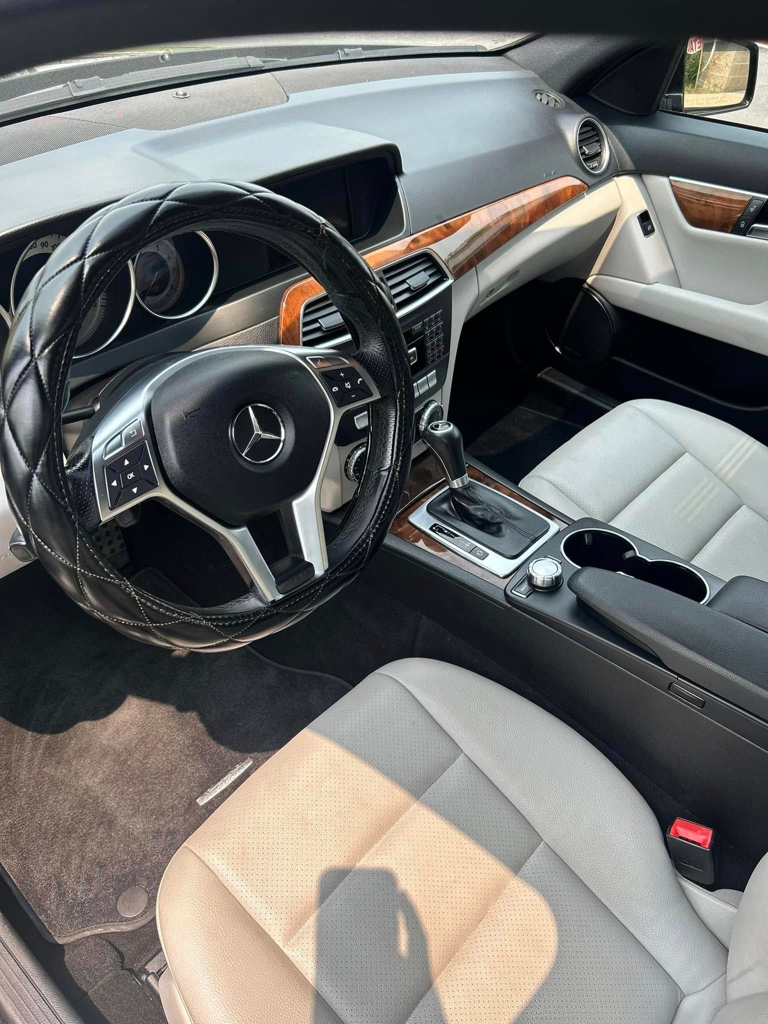 Interior of a black and beige Mazda car, showing the steering wheel, dashboard, and front seats.