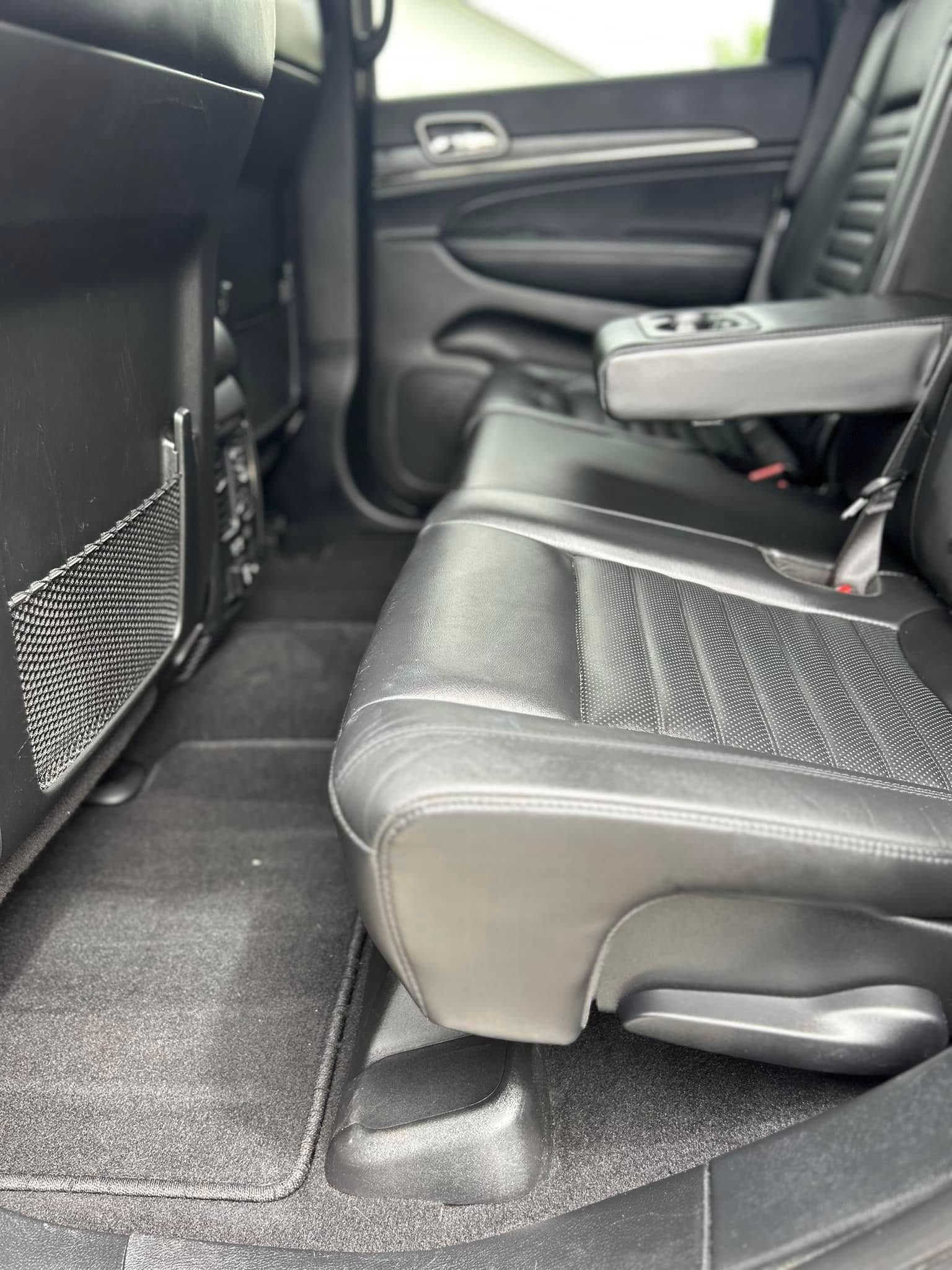 Car interior with black leather rear seats and a folded center armrest.
