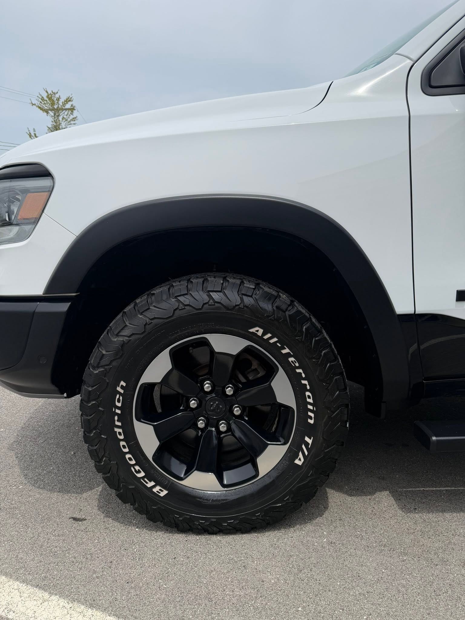White pickup truck with black wheel and tire parked outdoors on pavement