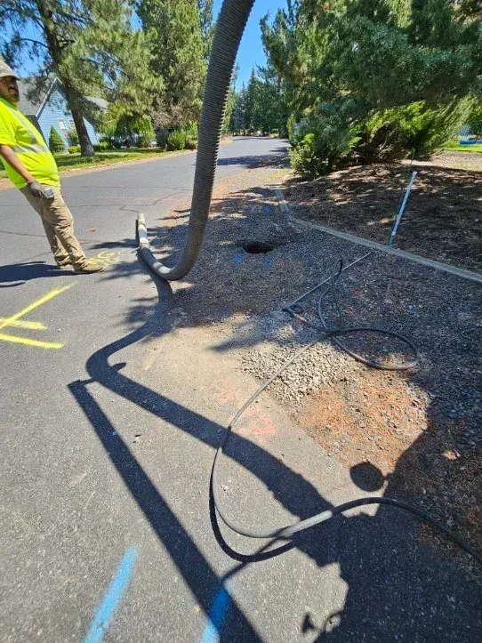 Utility worker standing by a damaged fallen tree branch across a road with a broken fence nearby