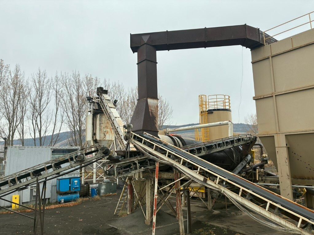 Collapsed industrial conveyor system at an outdoor plant, with bent metal beams and damaged structures
