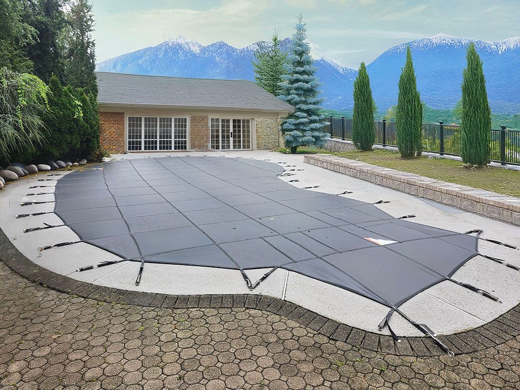 A large swimming pool with a cover on it in front of a house with mountains in the background.