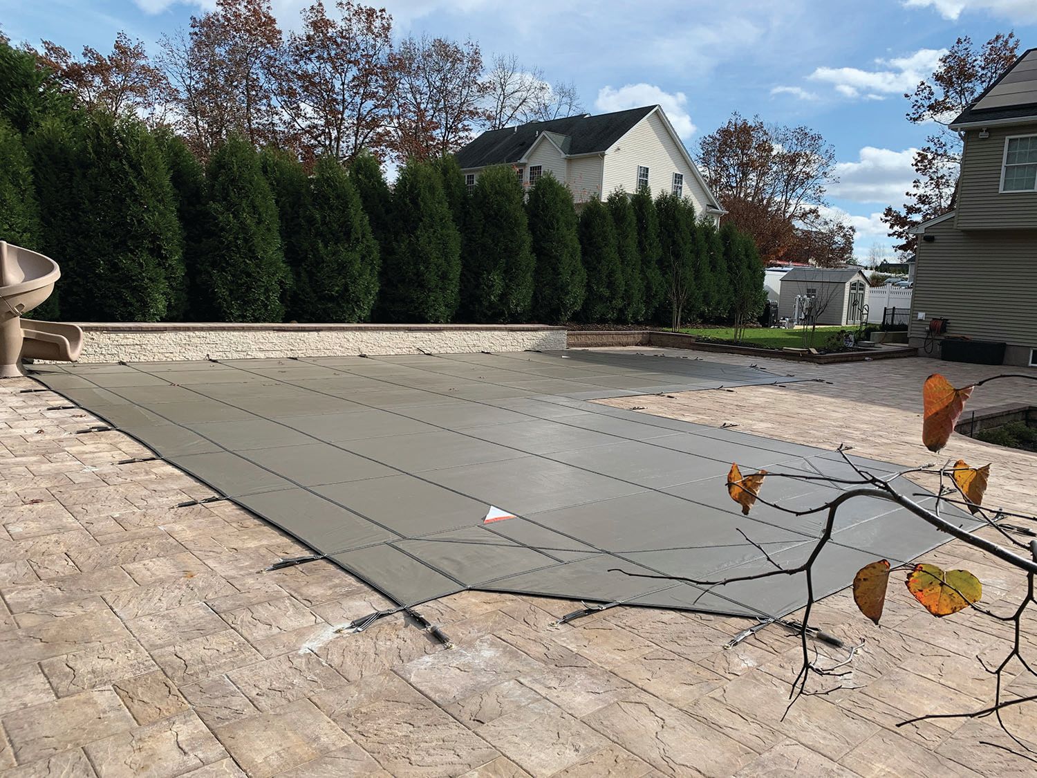 A swimming pool with a cover on it and a house in the background.