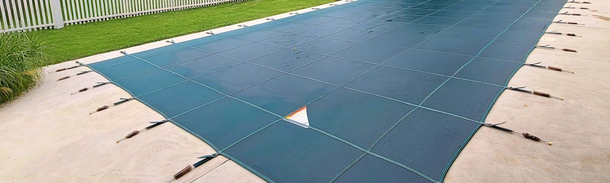A blue tarp is covering a swimming pool in a backyard.