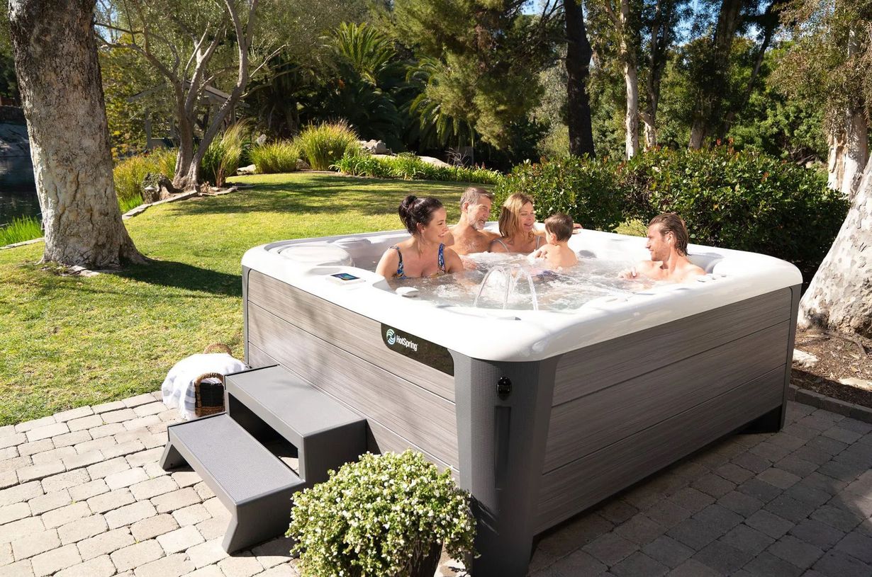 A group of people are sitting in a hot tub on a patio.