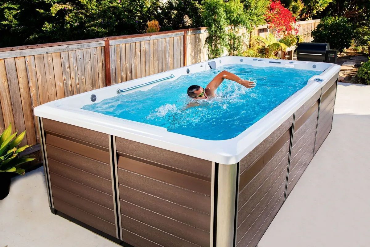 A man is swimming in a swimming pool on a patio.
