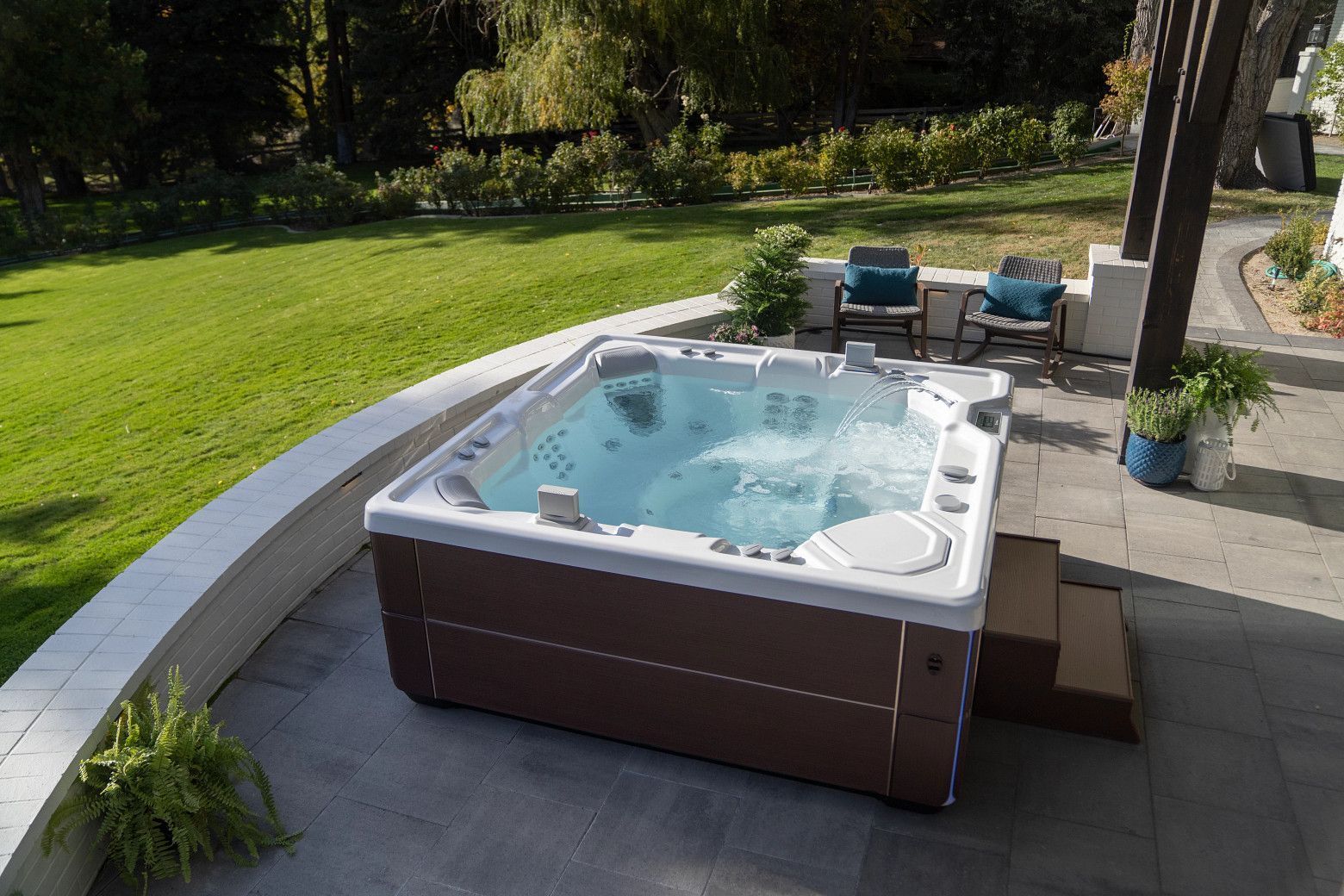 A hot tub is sitting on a patio next to a lush green lawn.