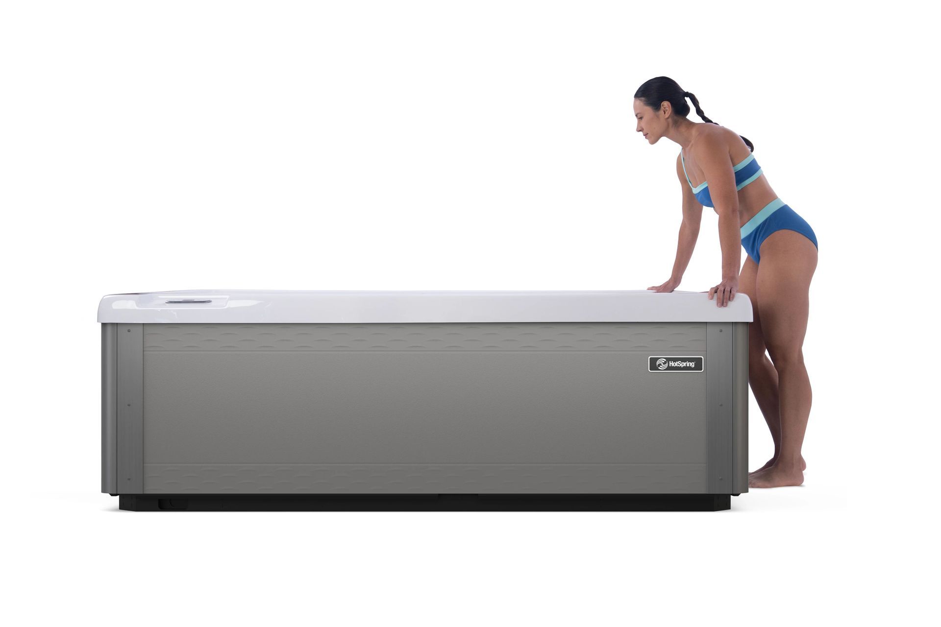 A woman in a bikini is standing next to a hot tub.