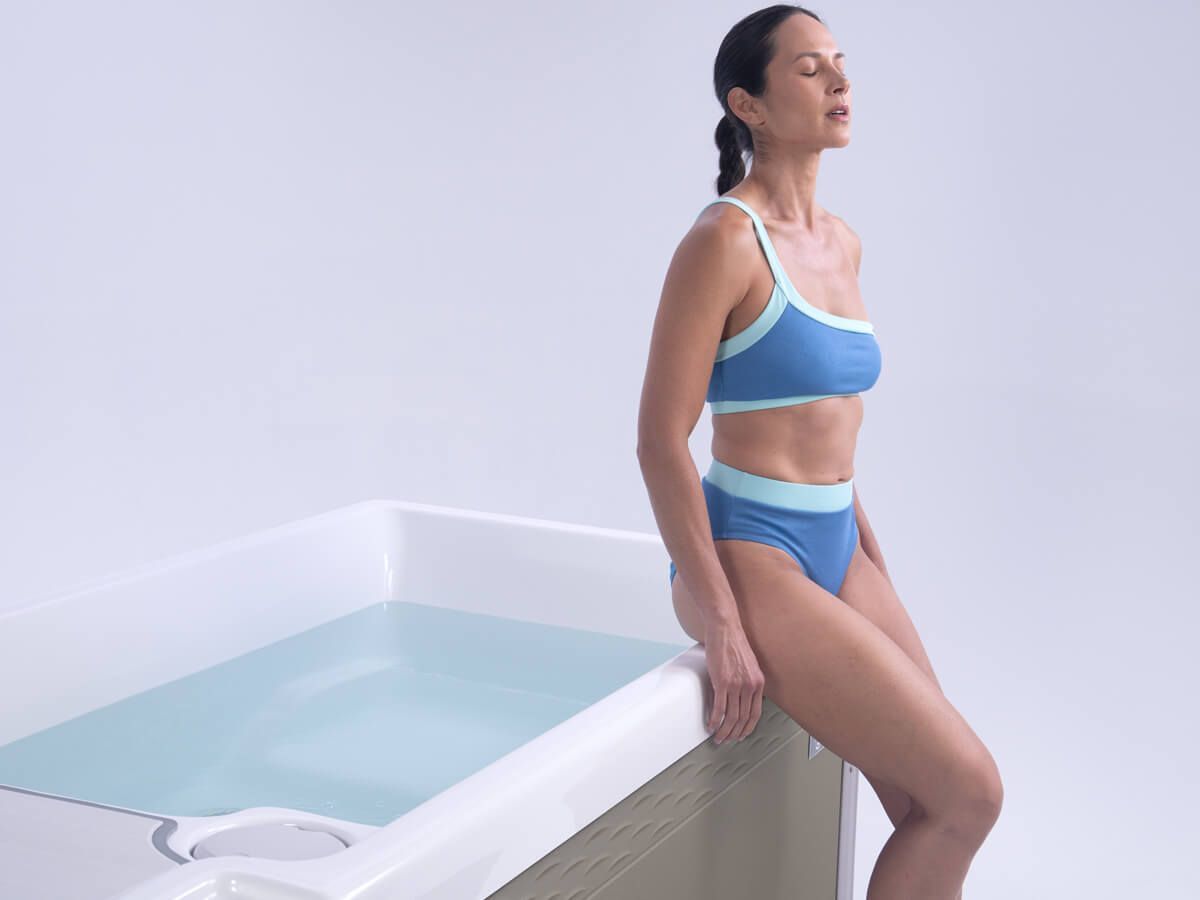 A woman in a bikini is leaning on the edge of a hot tub.