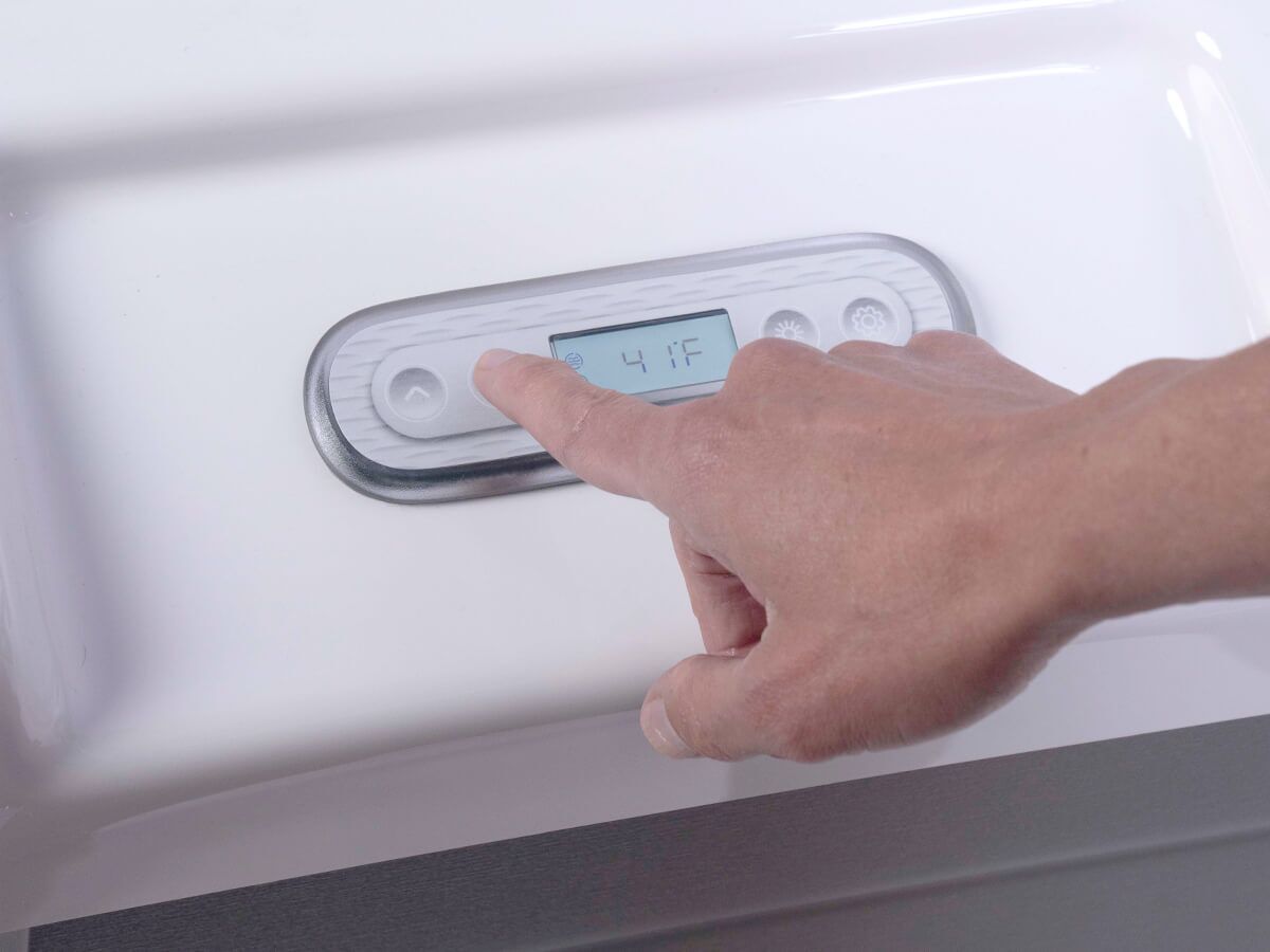 A person is pressing a button on a white wall.