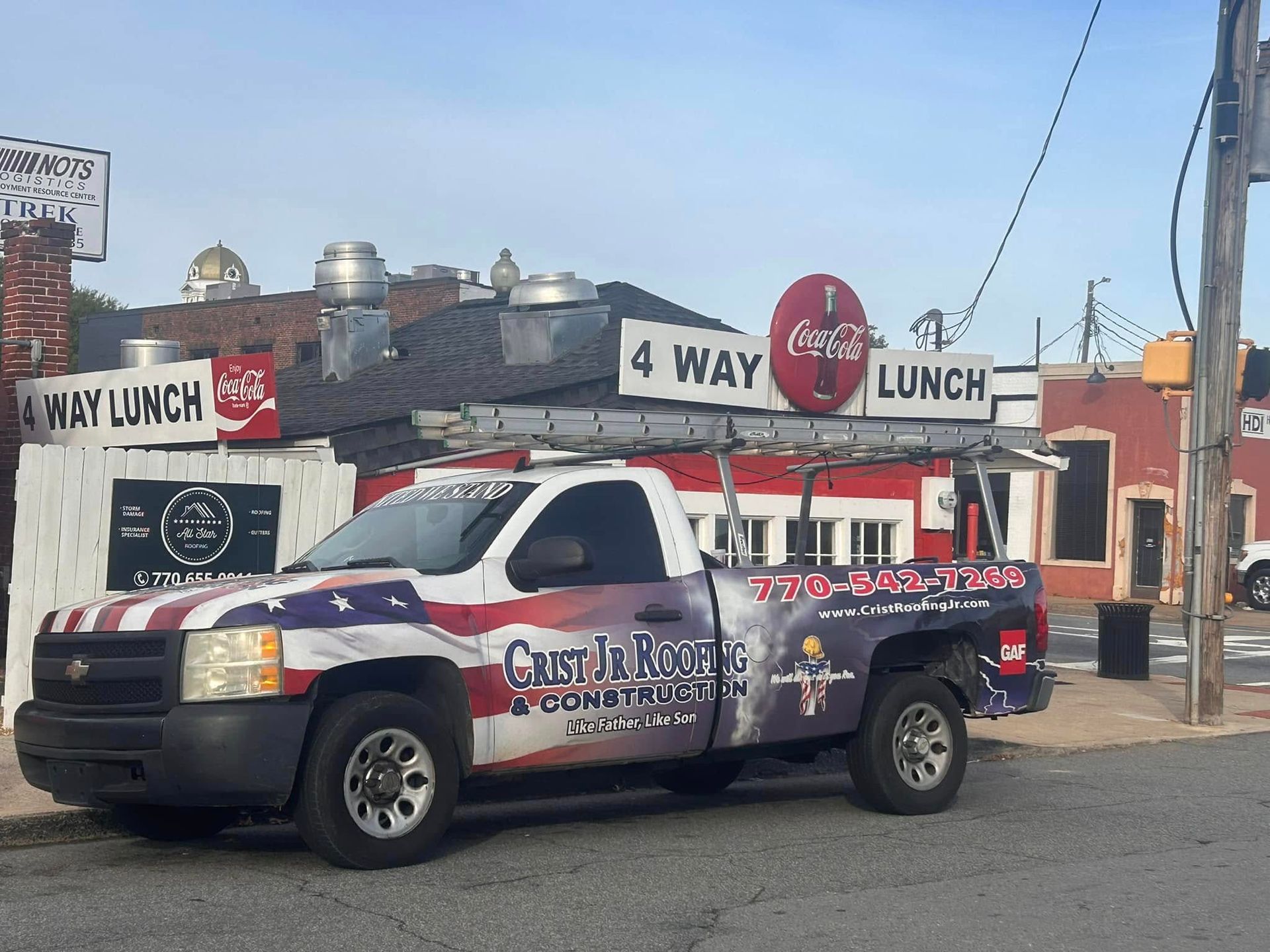White pickup truck with company graphics parked in front of a 4 Way Lunch restaurant