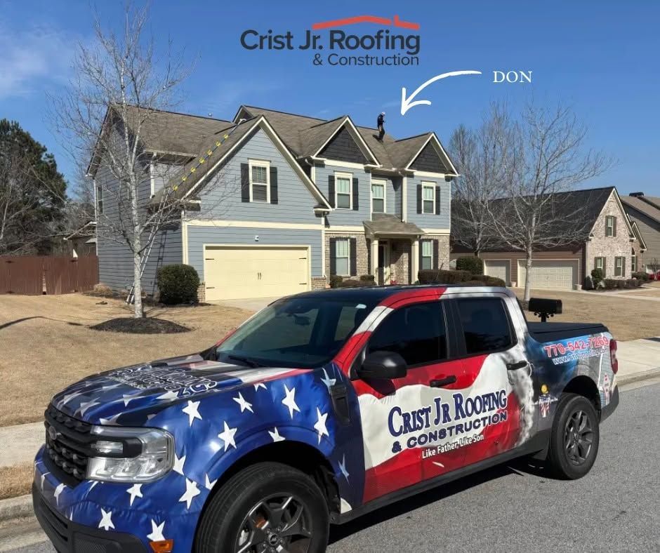 Christ Jr. Roofing & Construction truck parked in front of a house on a sunny residential street.