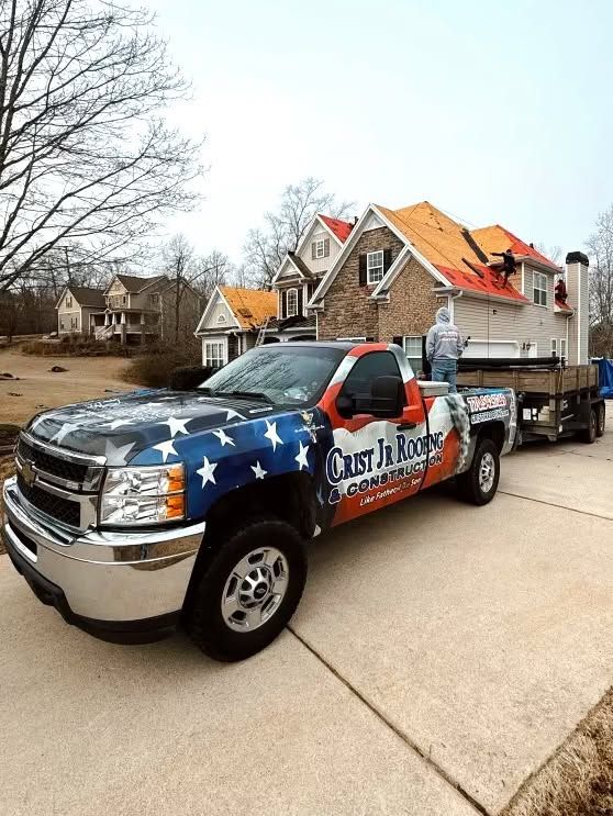 Patriotic truck and trailer parked in a suburban driveway with a person standing beside it