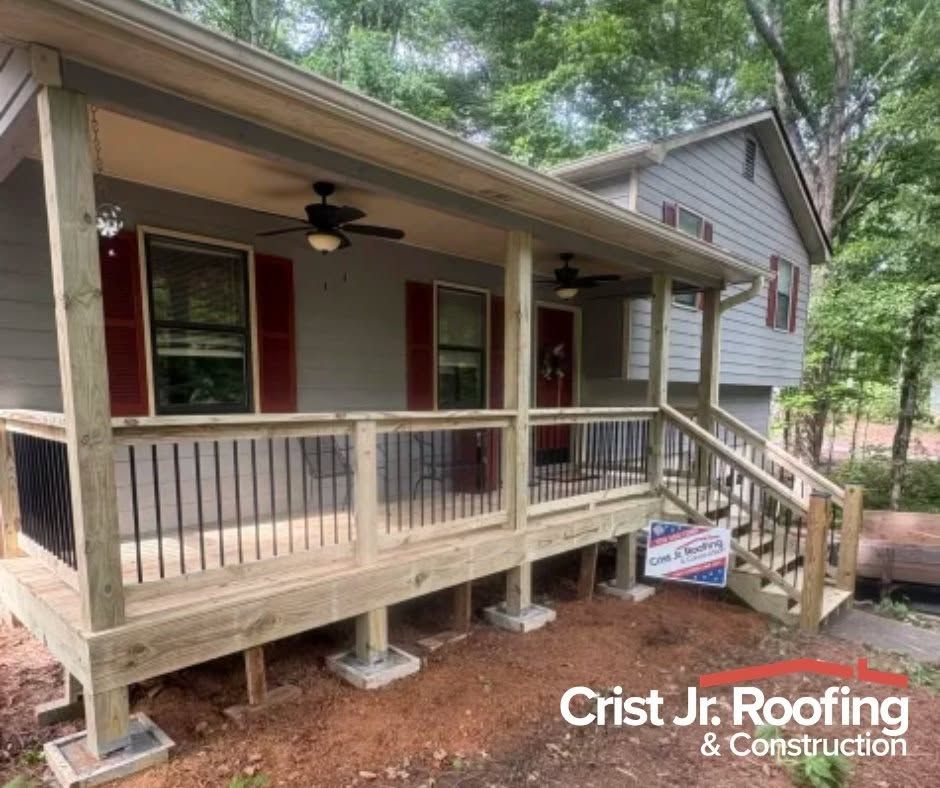 Front porch with new wood railing and steps on a house, with red shutters and Crist Jr Roofing watermark